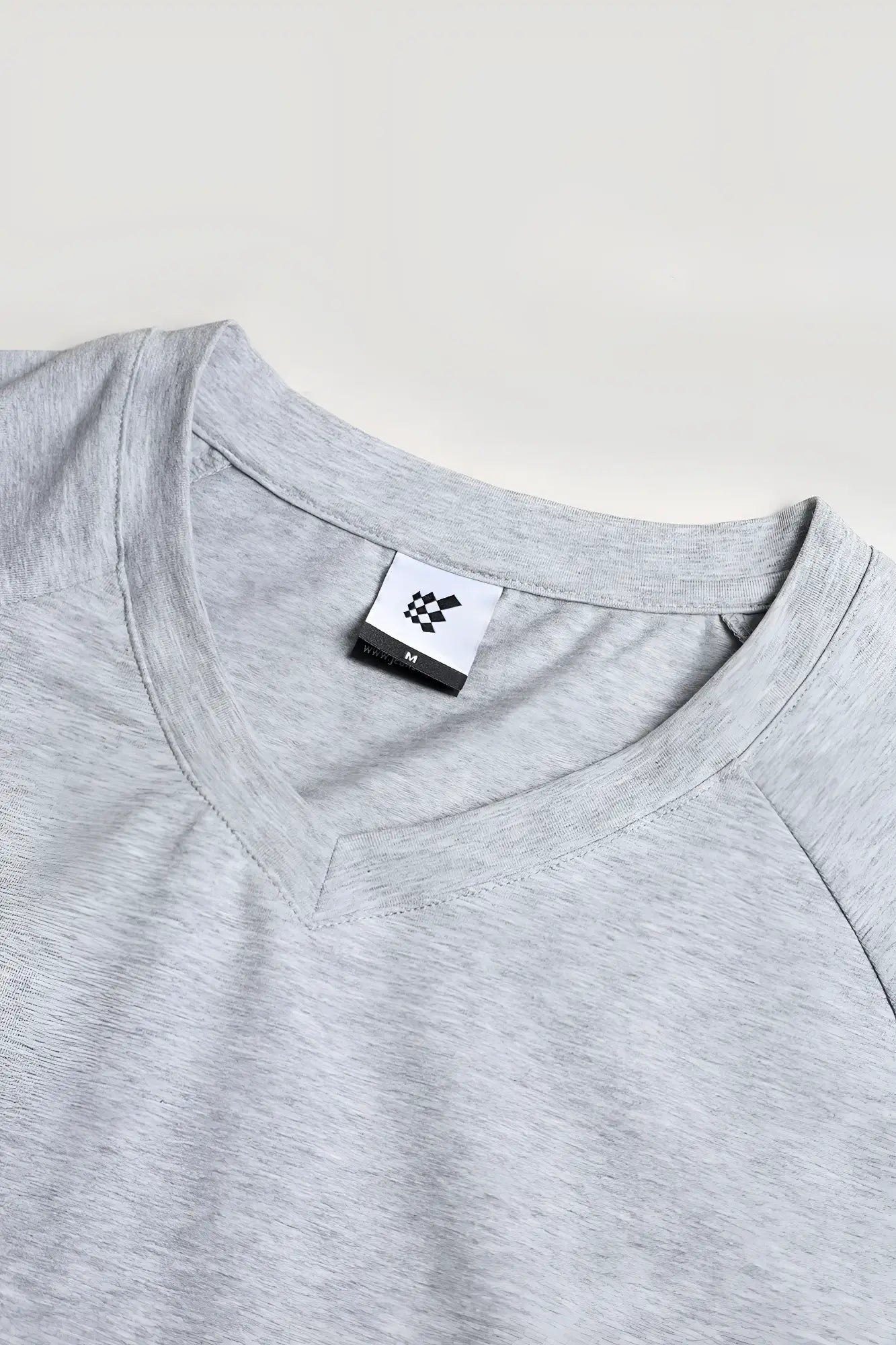 A heather gray v neck muscle-fit t-shirt with subtle textured fabric and a small white brand tag at the collar