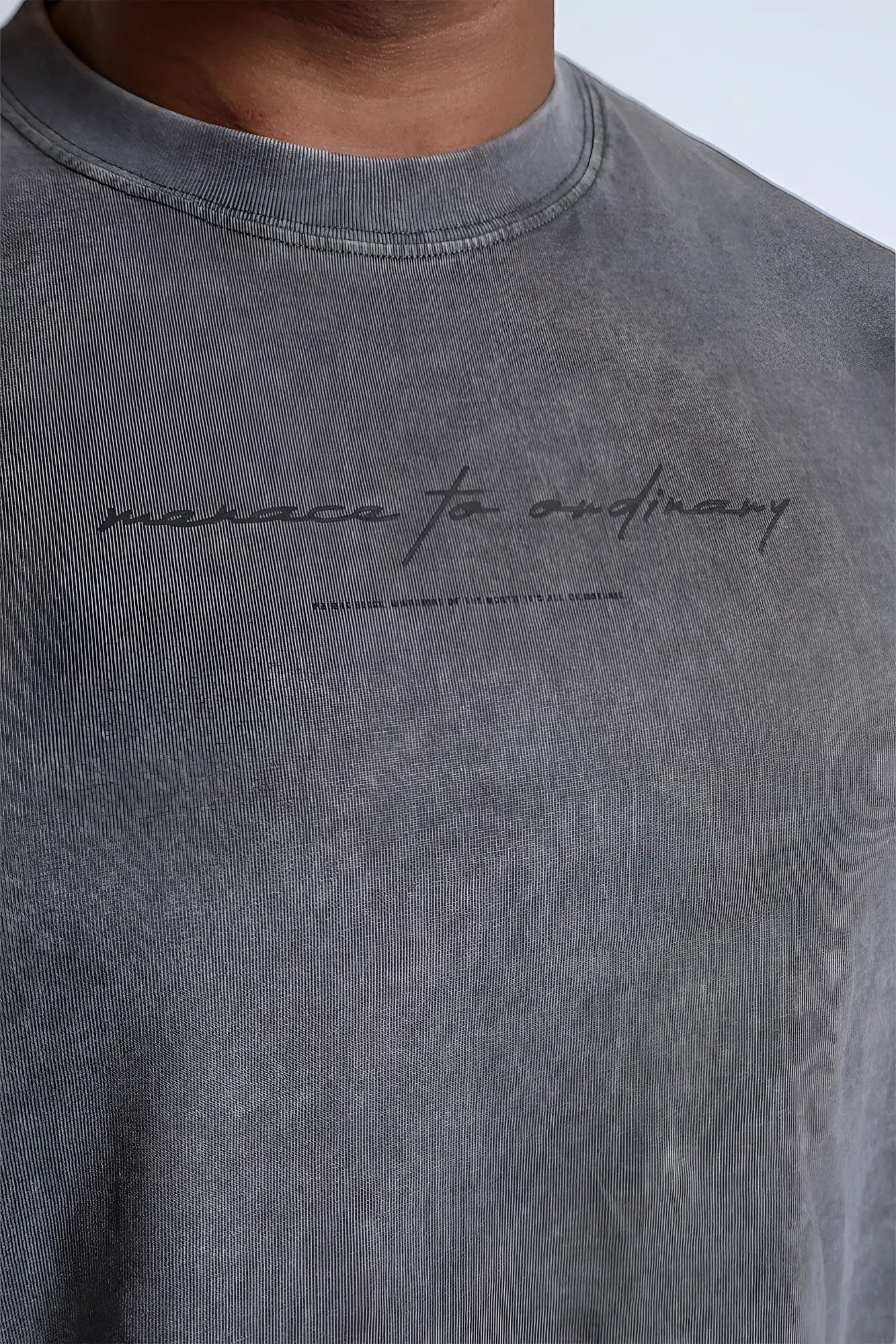 Vintage wash long sleeve t-shirt in storm gray cotton with a textured faded finish and black cursive manaca to ordinary text