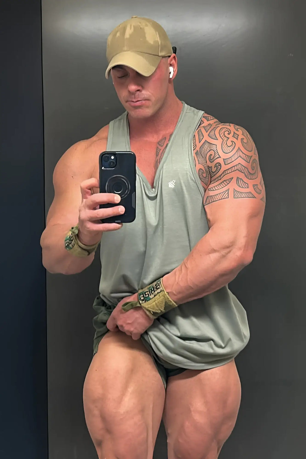A man wearing a beige cap and an olive green Jed North vital raw-hem sleeveless athletic tank top 2.0 gray