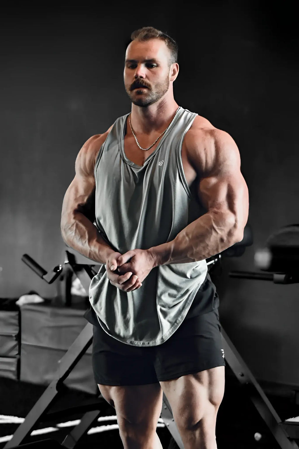 A muscular man wearing a gray Jed North Vital raw-hem sleeveless tank top 2.0 and black shorts