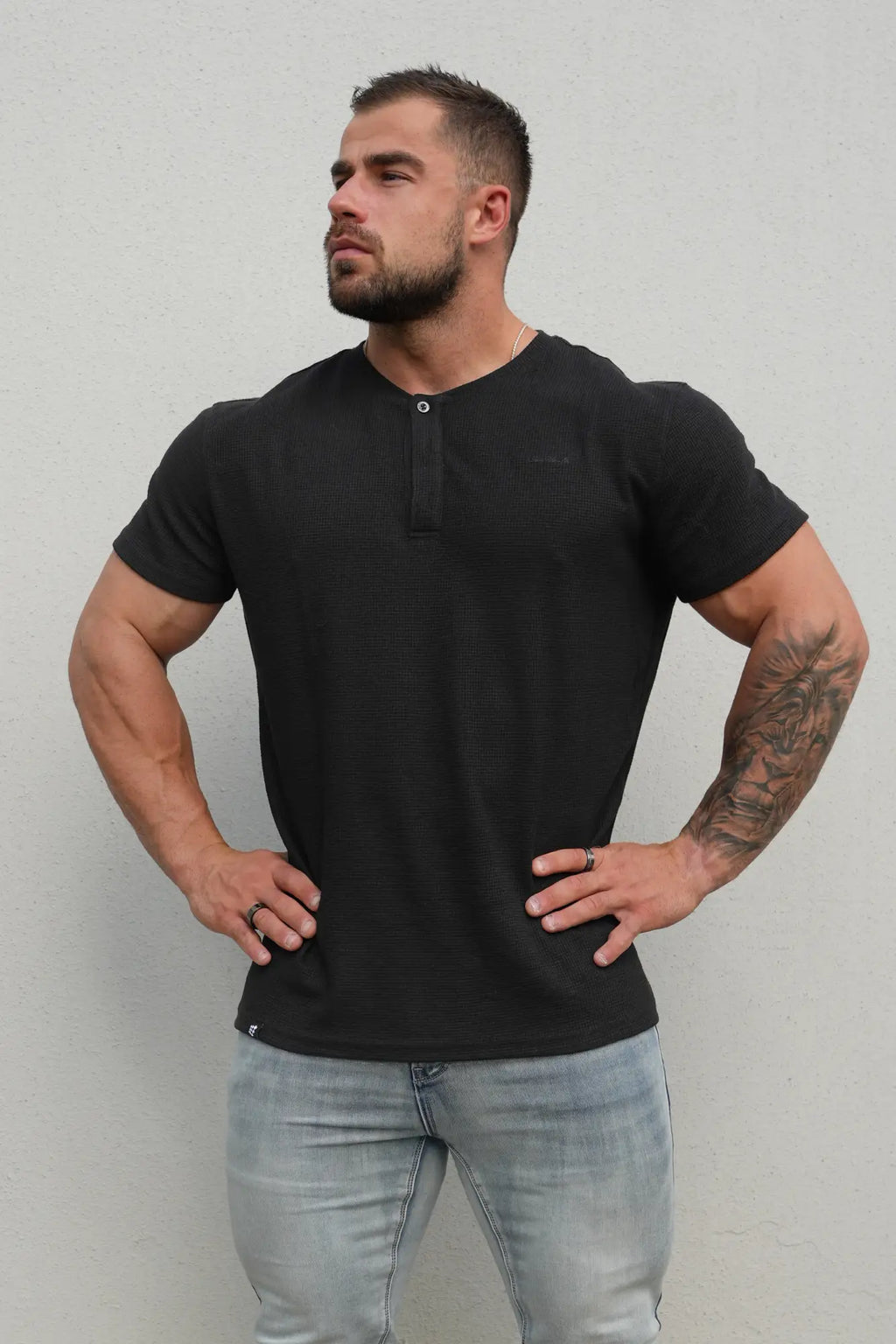 Black waffle henley t-shirt with textured fabric short sleeves and a single button at the neckline