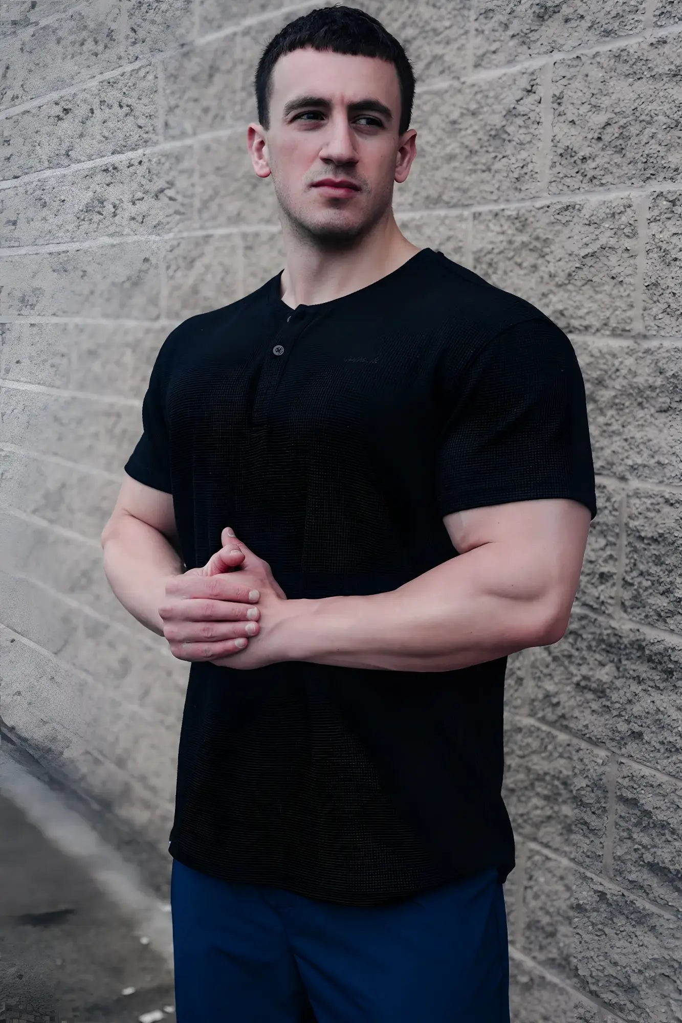 Black waffle henley t-shirt with textured fabric short sleeves and a single button at the neckline