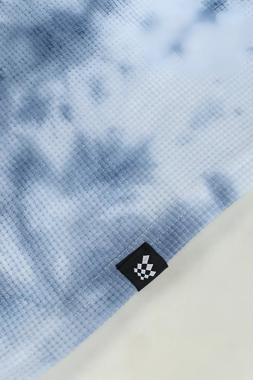 Light blue tie-dye waffle henley t-shirt made of waffle-knit fabric with black and white checkered brand tag