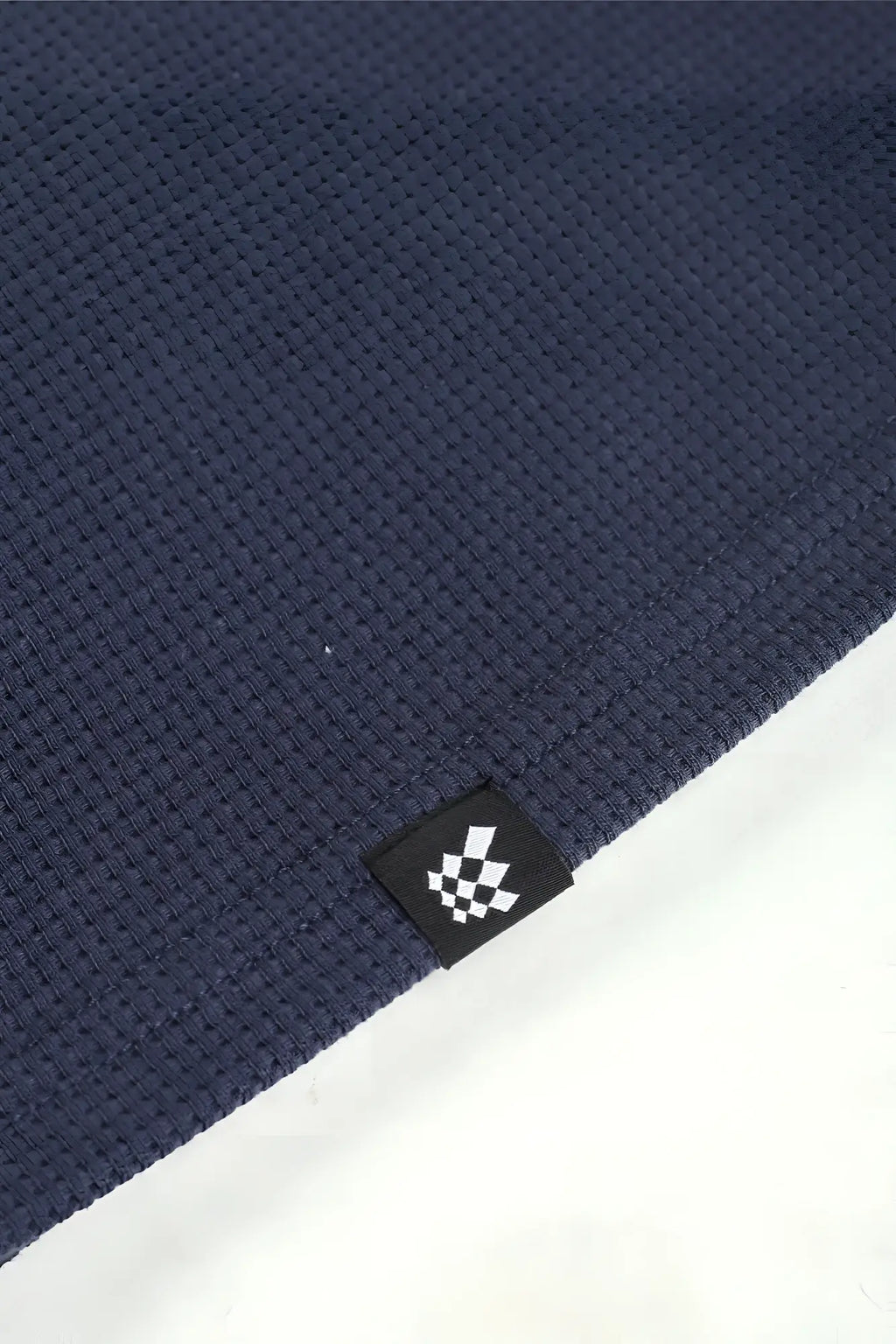 Dark blue waffle-knit fabric henley t-shirt with a small black tag featuring a white checkered logo dust blue color