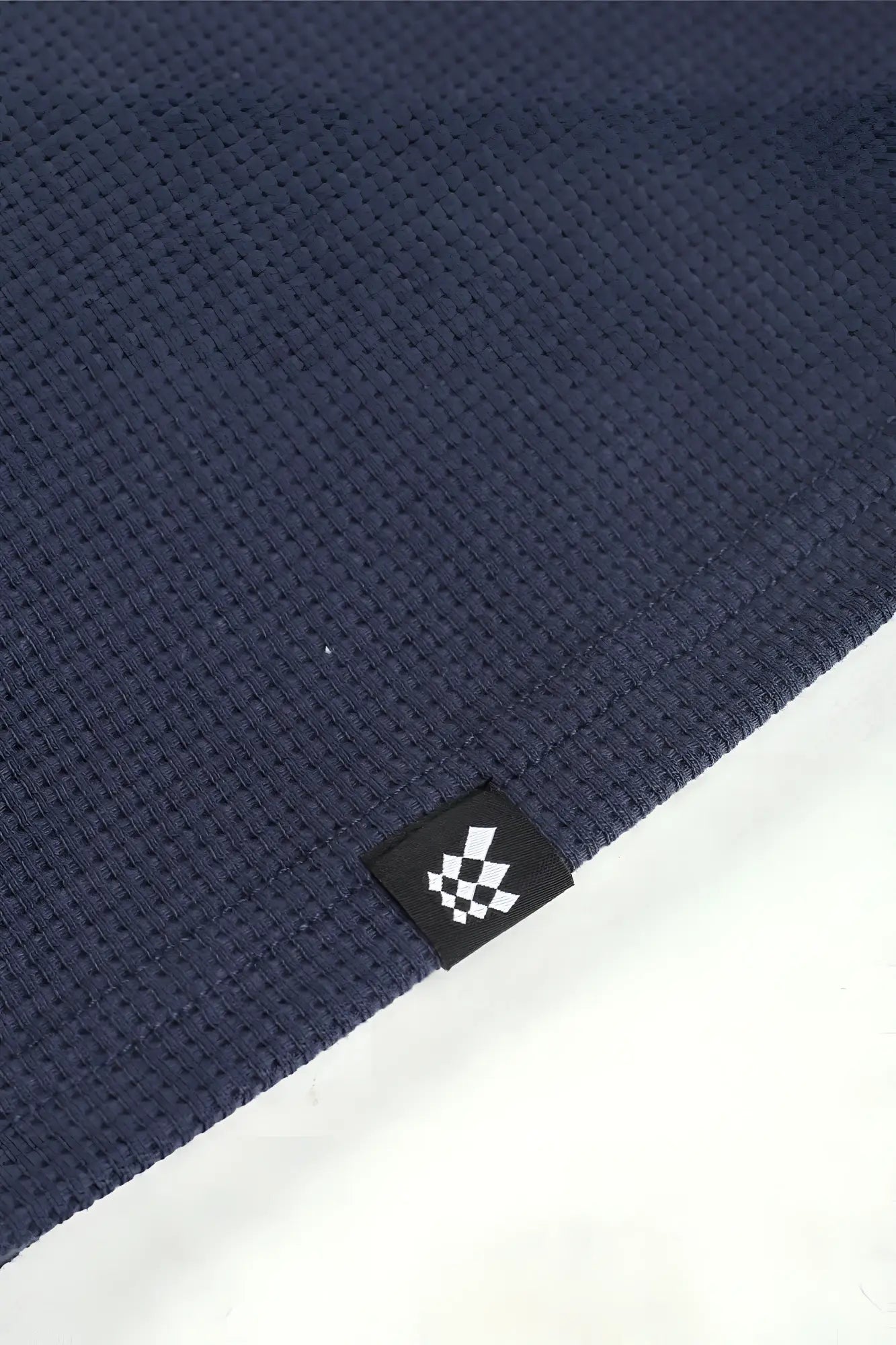 Dark blue waffle-knit fabric henley t-shirt with a small black tag featuring a white checkered logo dust blue color