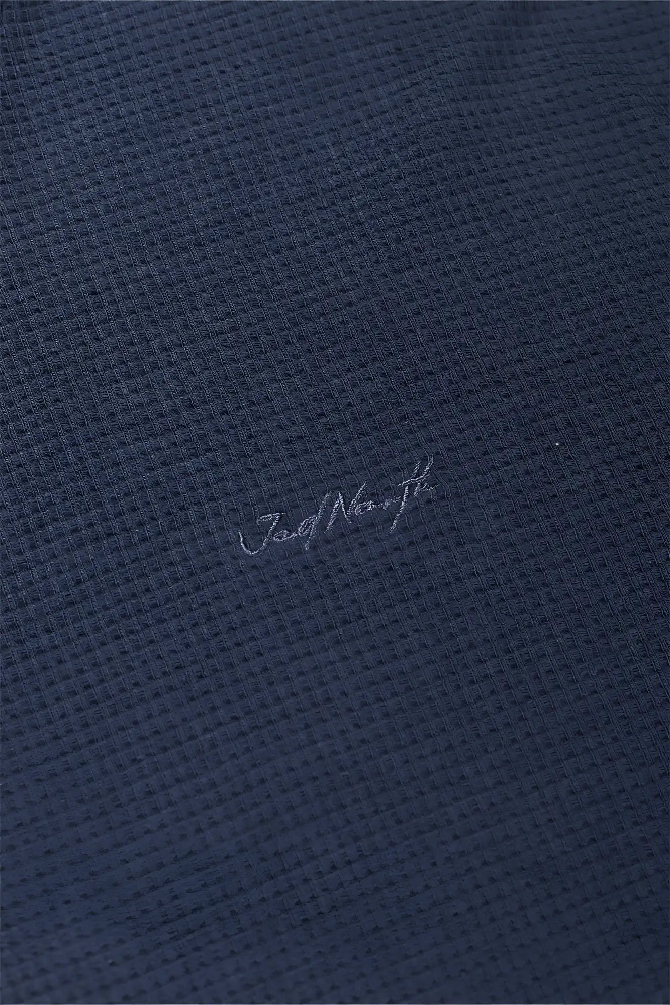Dark blue waffle-knit polo shirt with subtle jord norrth embroidery in a waffle henley t-shirt style dusty blue color