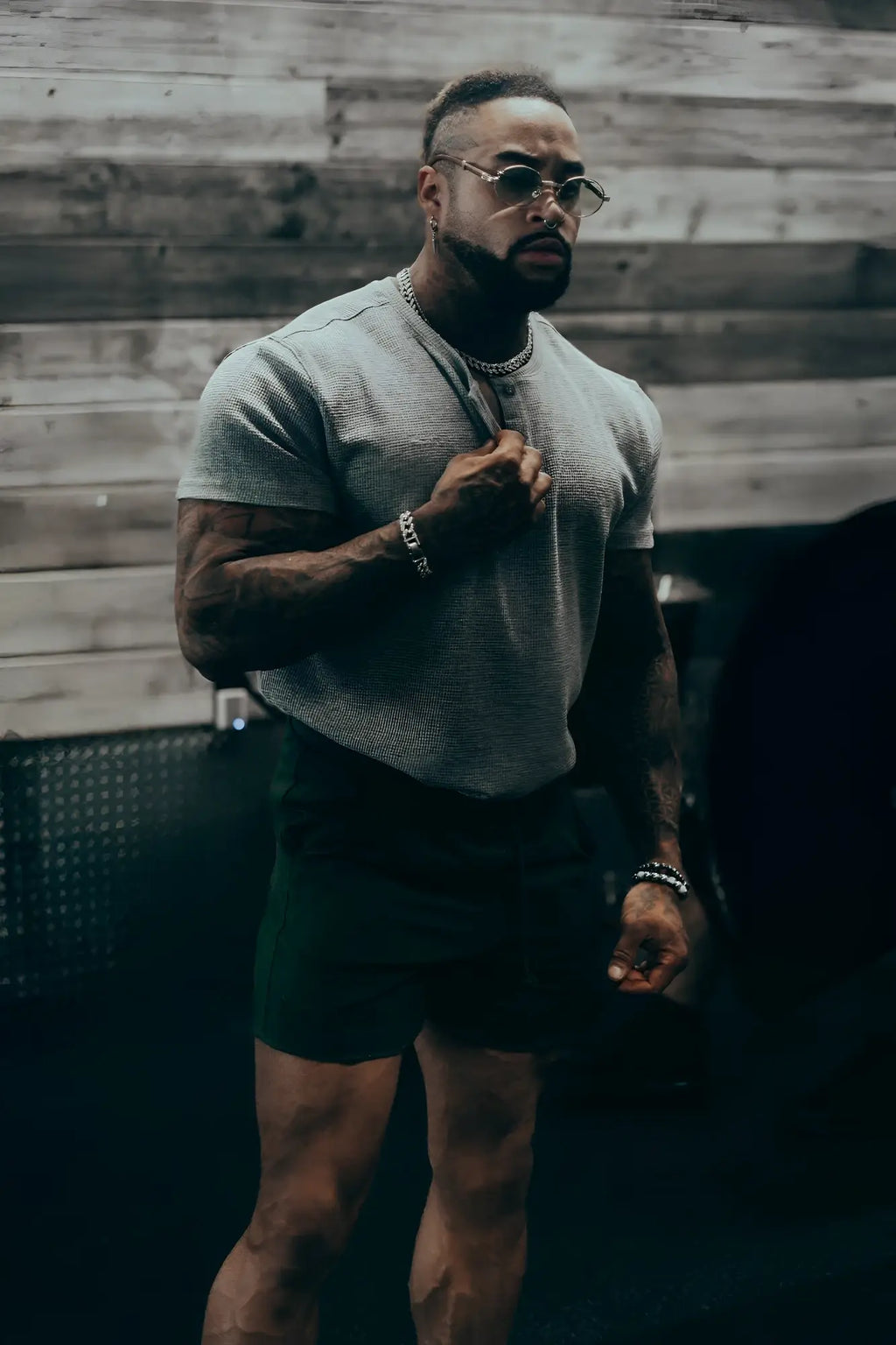 A man wearing a light gray waffle henley t-shirt made of textured fabric with black shorts