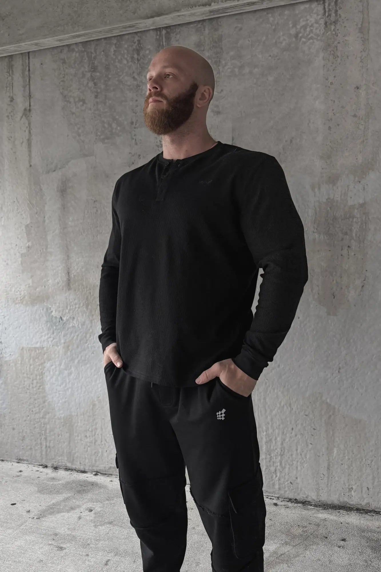 Black waffle knit henley long sleeve t-shirt with subtle chest logo and textured fabric for casual wear