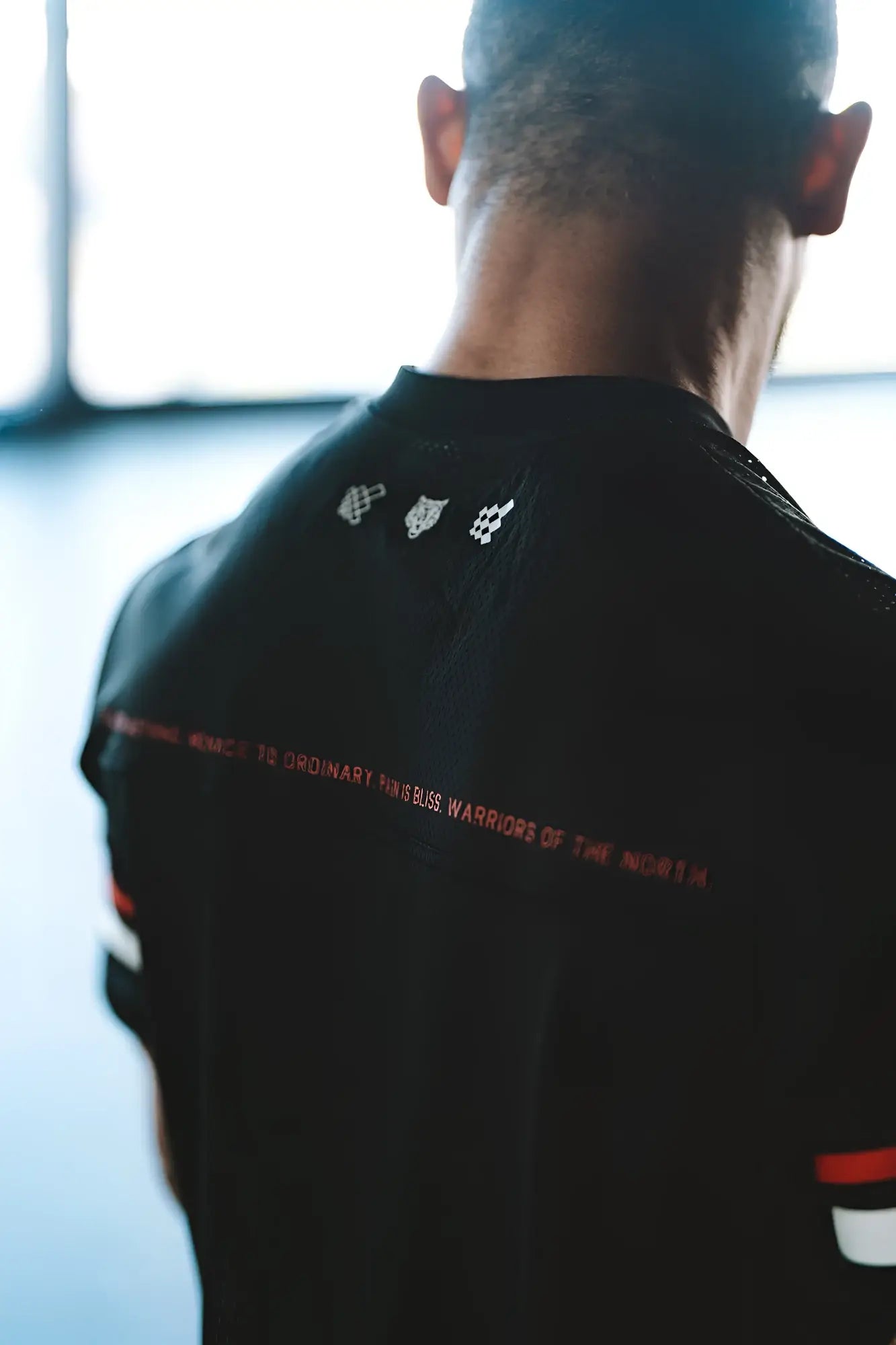 Back view of jed north warrior v neck jersey black athletic shirt with red text and white logo details on the back