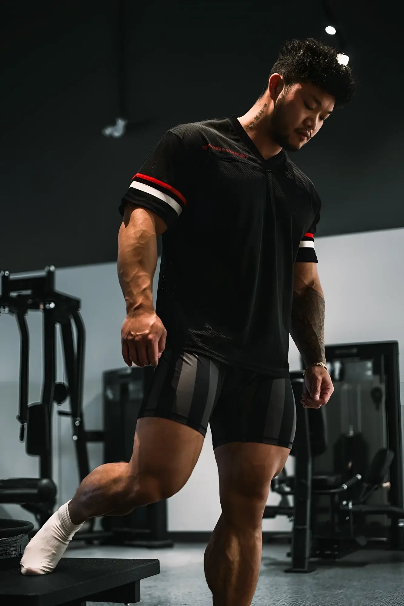 Muscular man wearing jed north warrior v-neck jersey black with red and white striped sleeves in gym setting