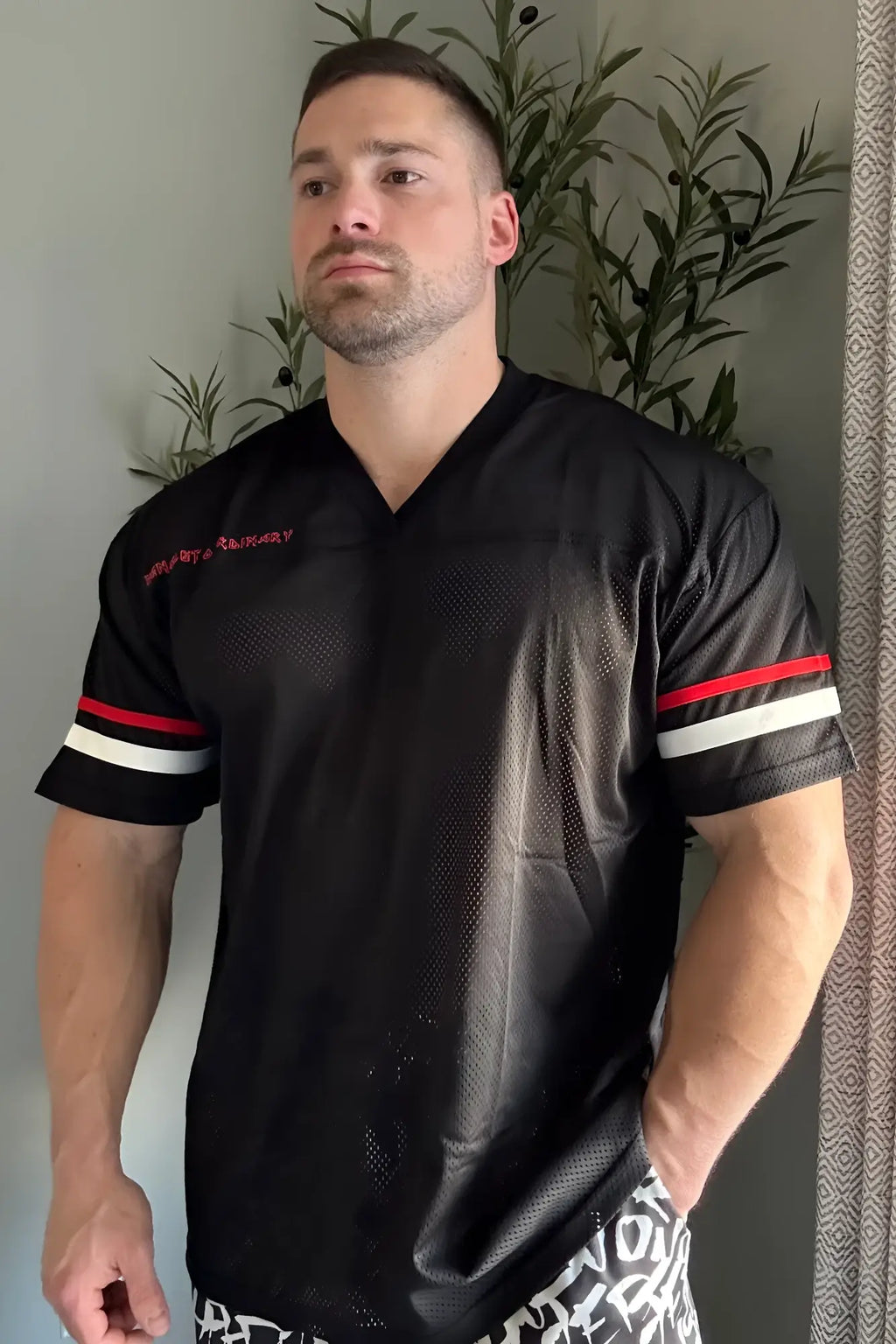 Black mesh Jed North Warrior V-neck football jersey with red and white striped sleeves and embroidered chest text