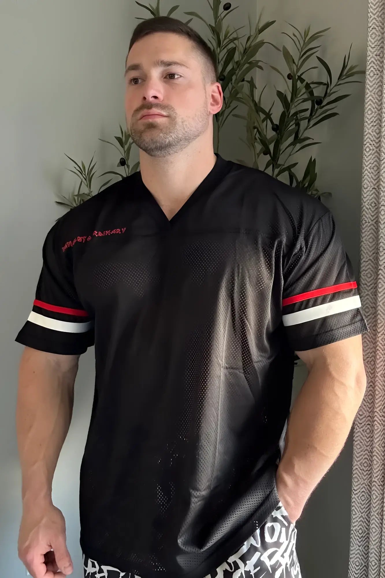 Black mesh Jed North Warrior V-neck football jersey with red and white striped sleeves and embroidered chest text