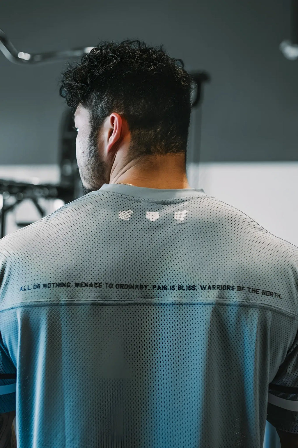 Back of jed north warrior v neck jersey in light blue and gray mesh with textured pattern and white shoulder logos