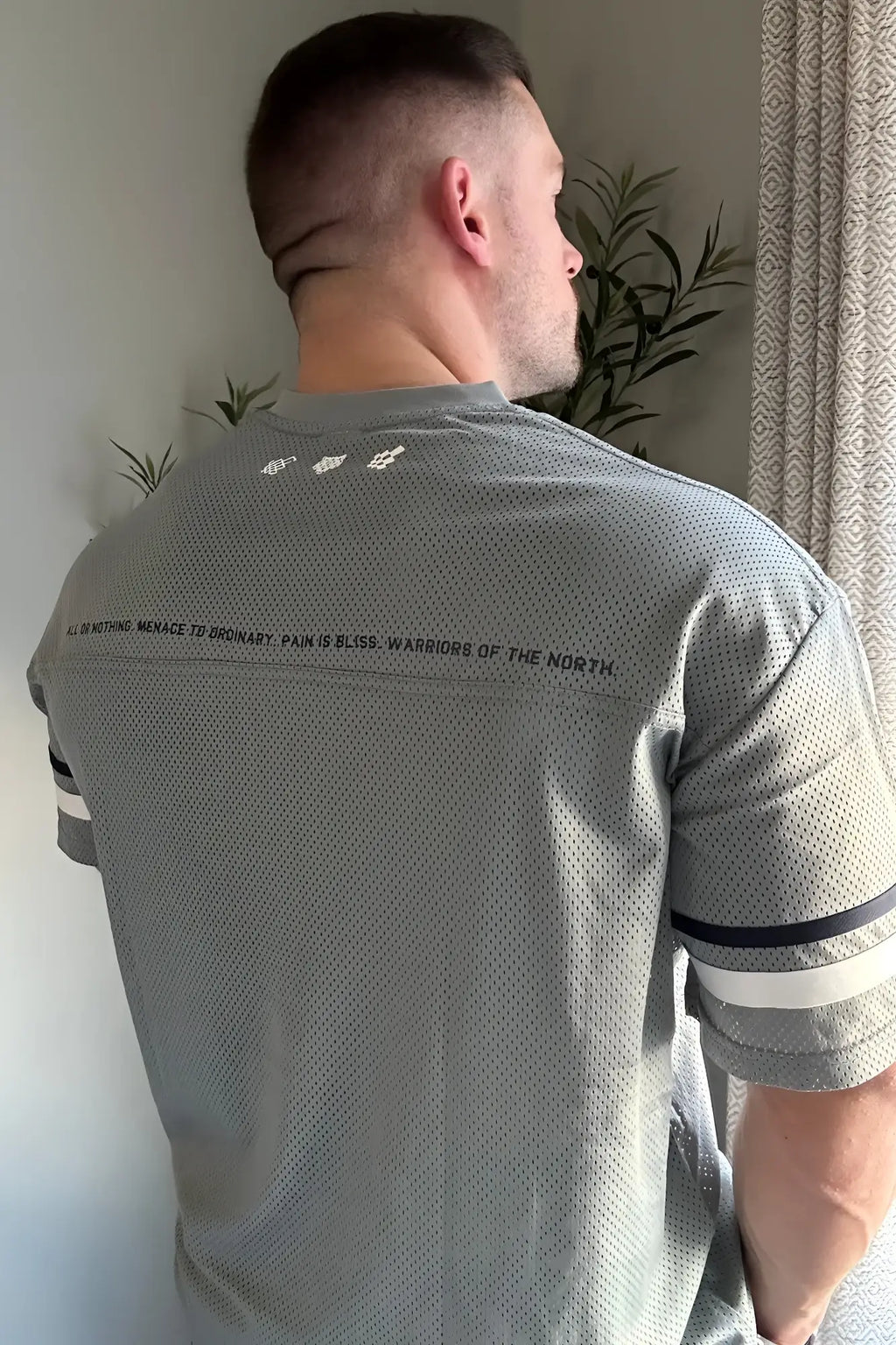 Back view of jed north warrior v-neck gray mesh athletic shirt with black and white striped sleeves and motivational quote
