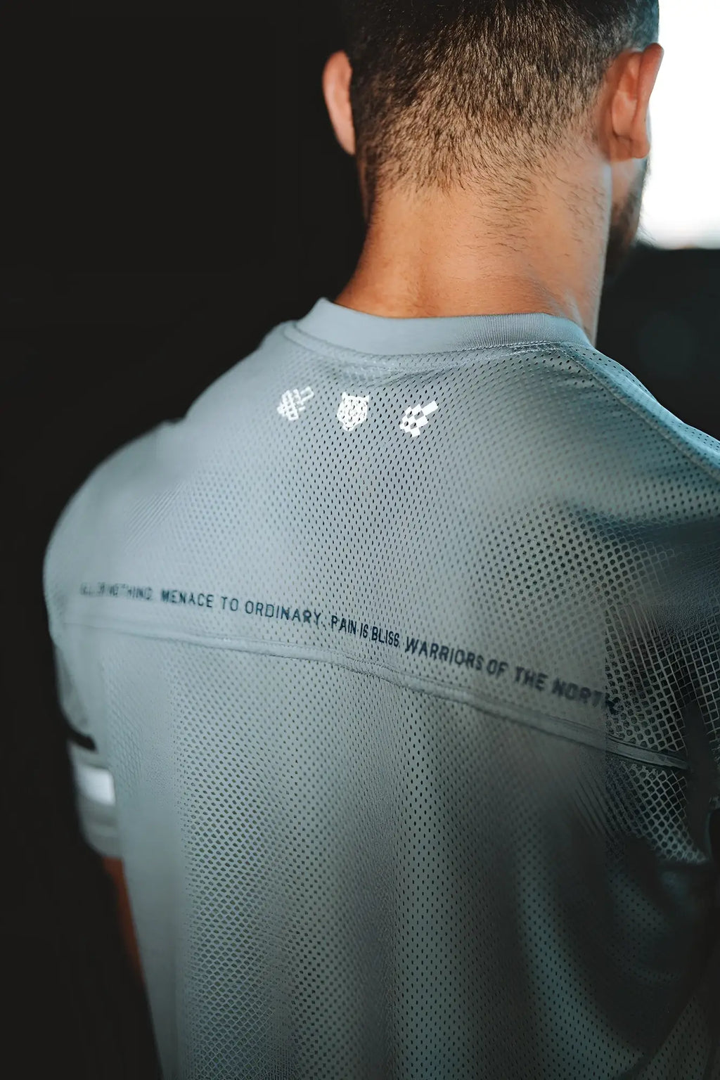 Back view of jed north warrior v-neck gray mesh athletic shirt with subtle white logo and black text across the back