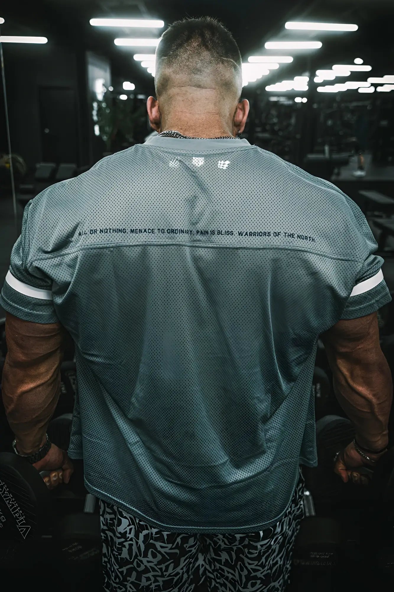 Back side of jed north warrior v neck jersey gray mesh athletic shirt with white sleeve stripes and black text