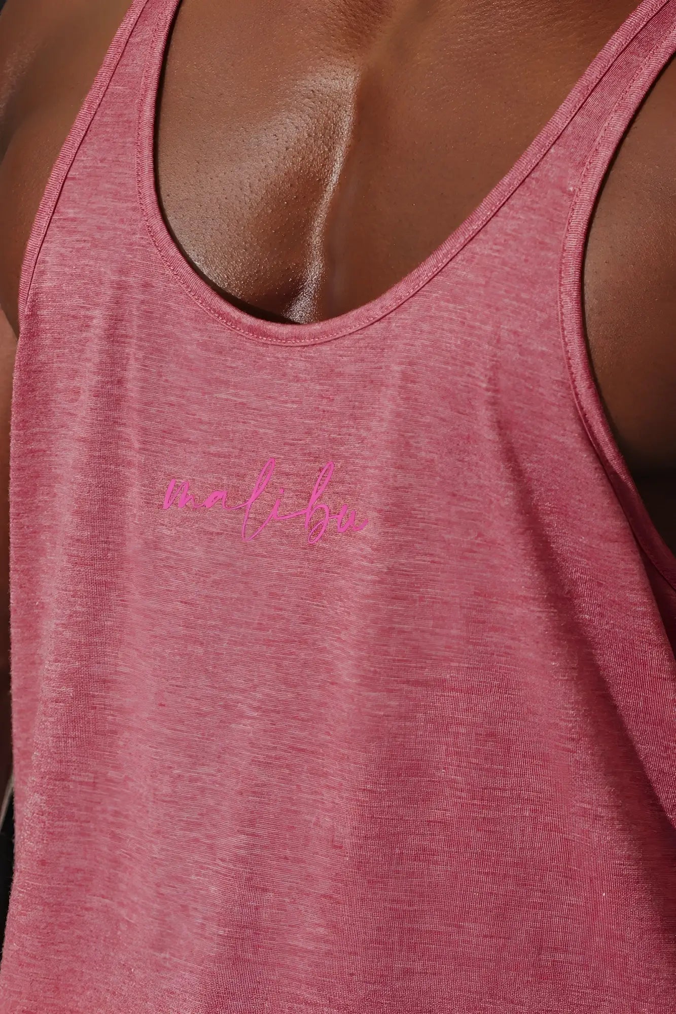 A soft pink heathered jj classic workout stringer tank top with malibu script embroidered in bright pink thread