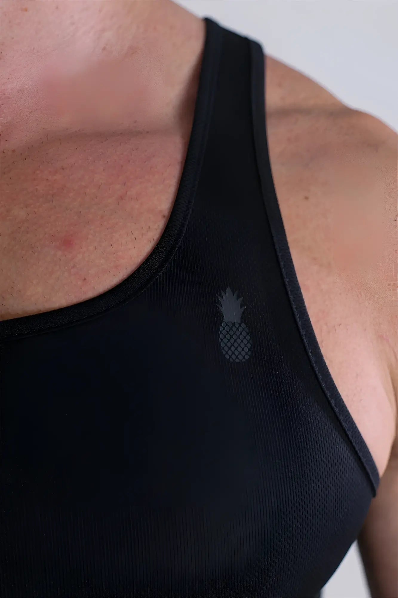 Black jj dry-cool crop tank top with subtle gray pineapple logo designed for athletic performance and breathability