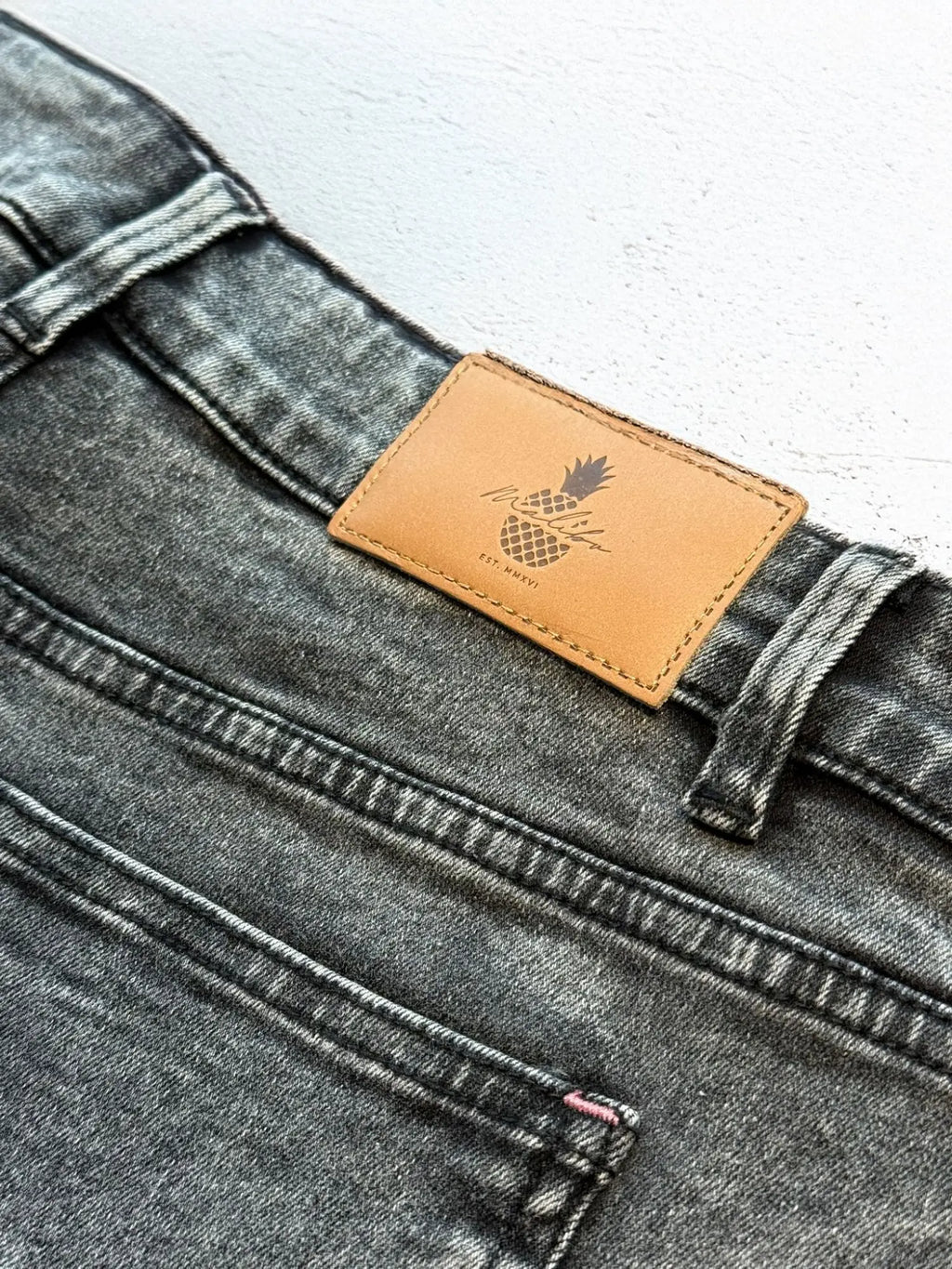 Dark gray acid washed distressed denim booty shorts with tan leather pineapple patch on the back