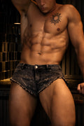 Acid washed distressed booty shorts in black black distressed denim with frayed hem shown from the back side
