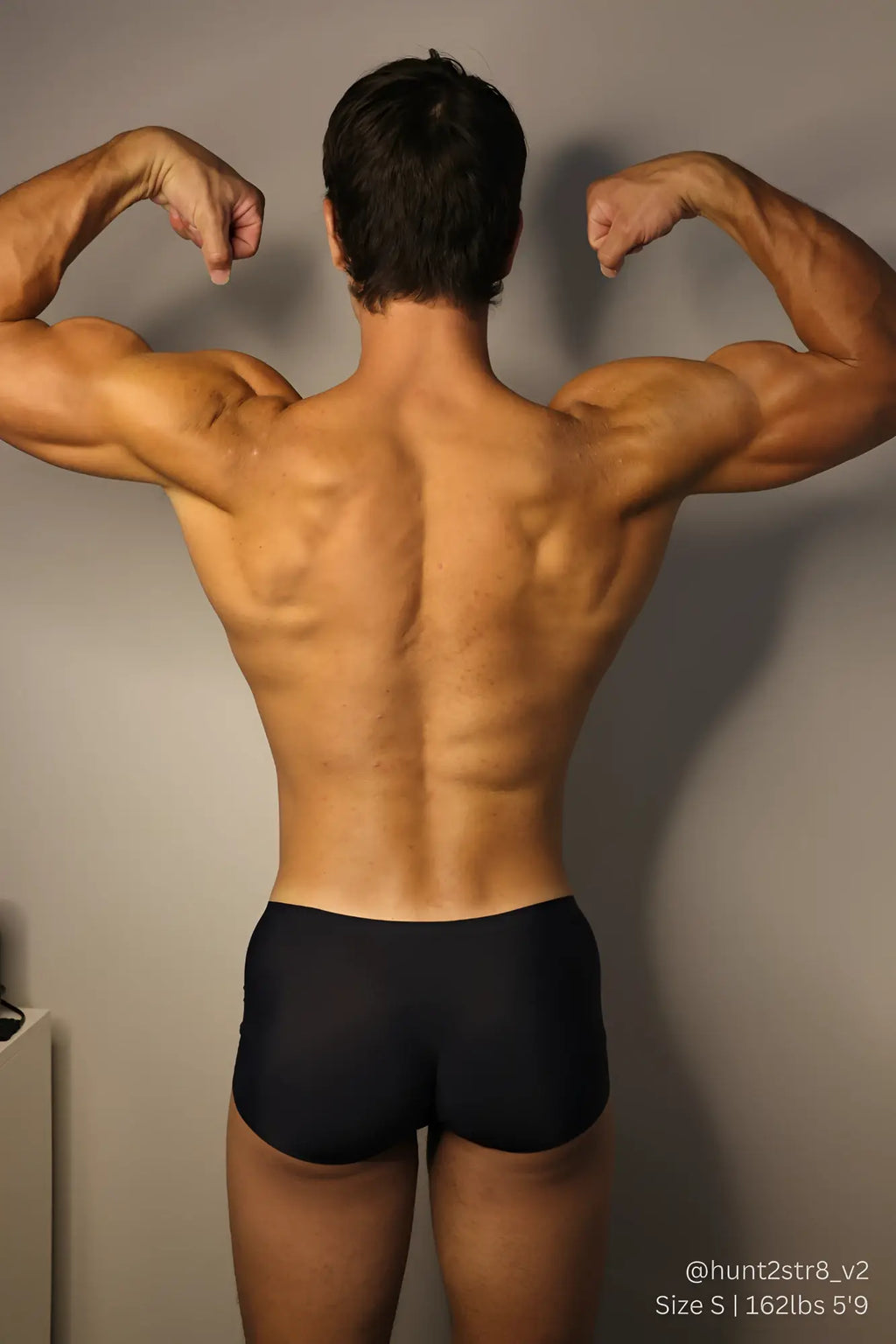 A muscular man wearing come-over silky seamless boxer briefs in midnight black showing the front view
