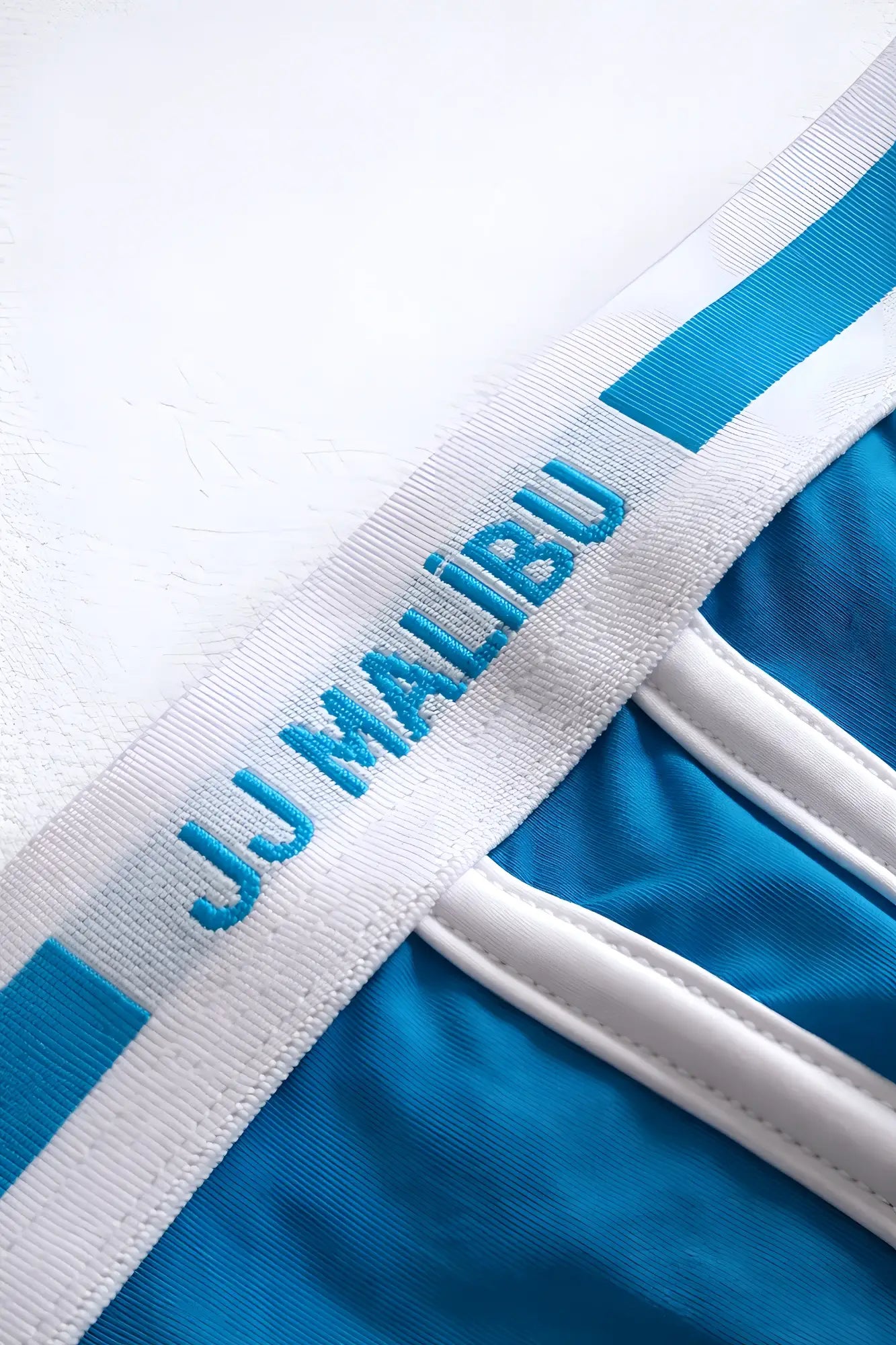 Blue and white jj malibu branded waistband with embroidered logo on on-display jockstrap back side