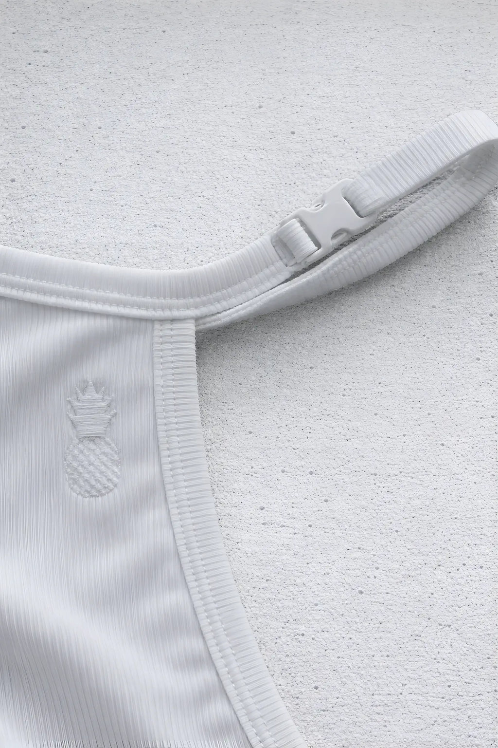White ribbed fabric strap with plastic buckle and embroidered pineapple detail on the back of polar white g string v back jockstrap