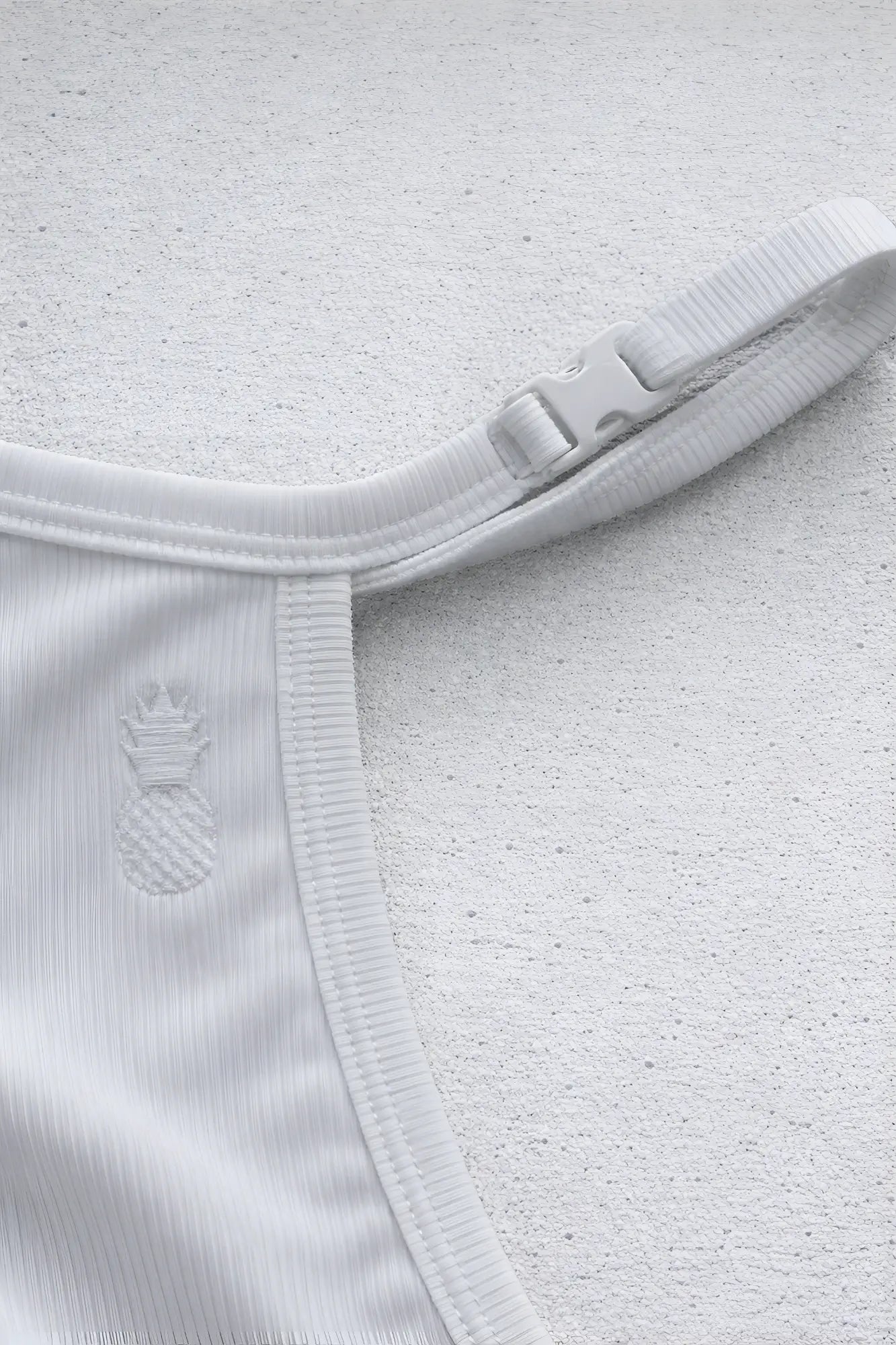 White ribbed fabric strap with plastic buckle and embroidered pineapple detail on the back of polar white g string v back jockstrap