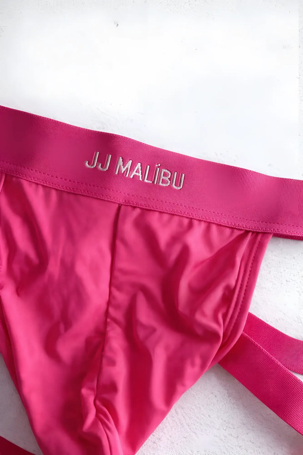 Bright pink host-or-travel adjustable jock thong with satin finish and embroidered jj malibu waistband visible from back