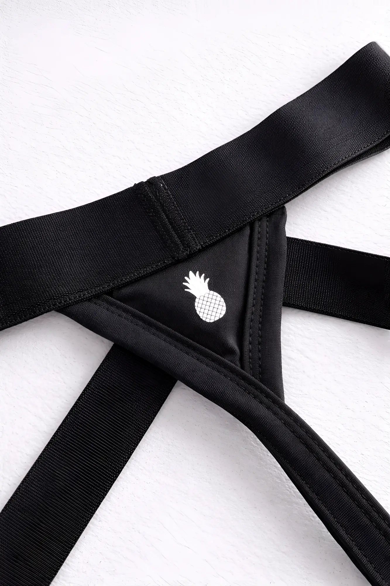 Host-or-travel adjustable jock thong in midnight black with black elastic bandeau and white pineapple emblem