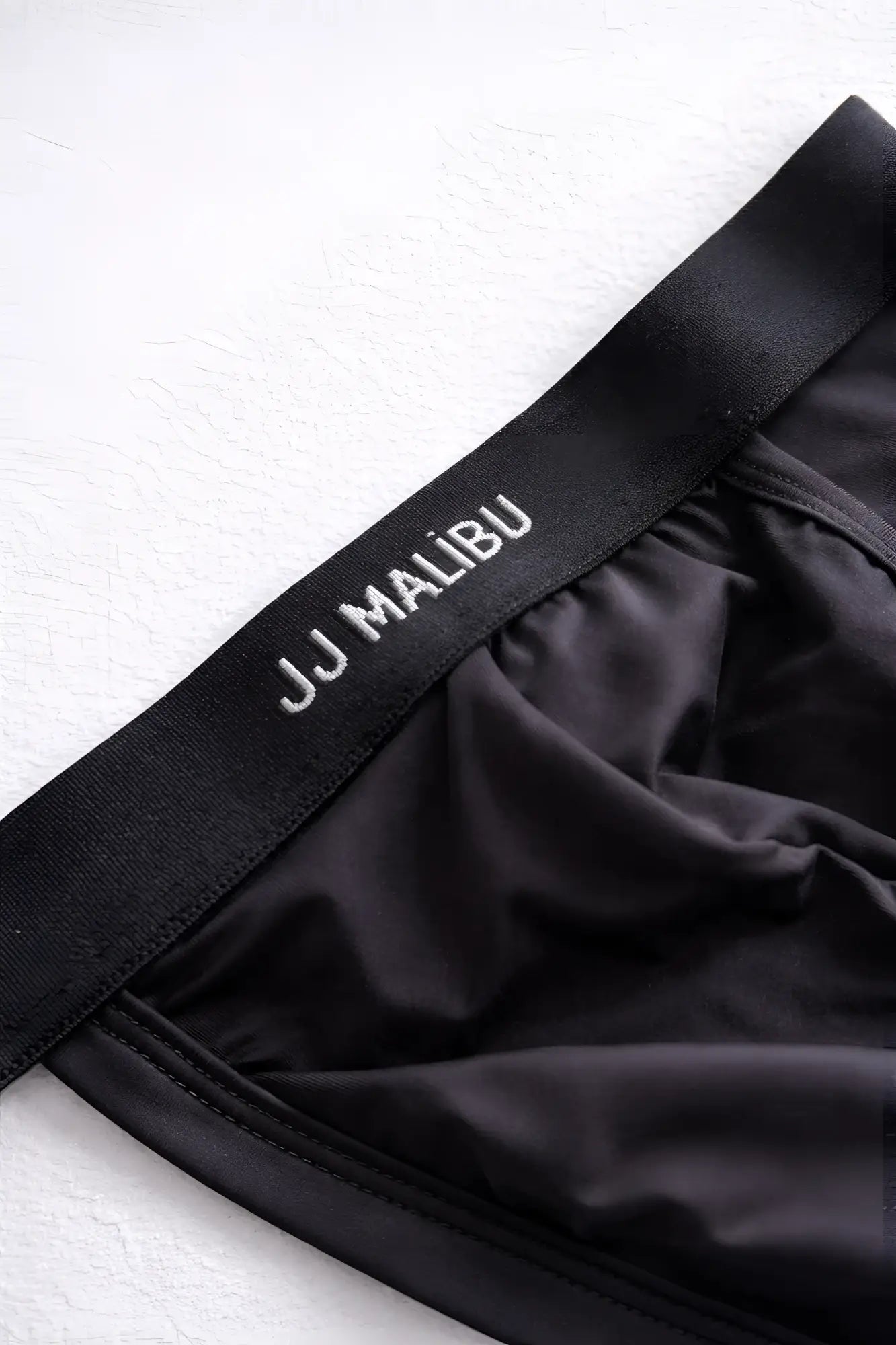 Black Host-or-Travel adjustable jock thong made of smooth stretchy fabric with white embroidered waistband branding