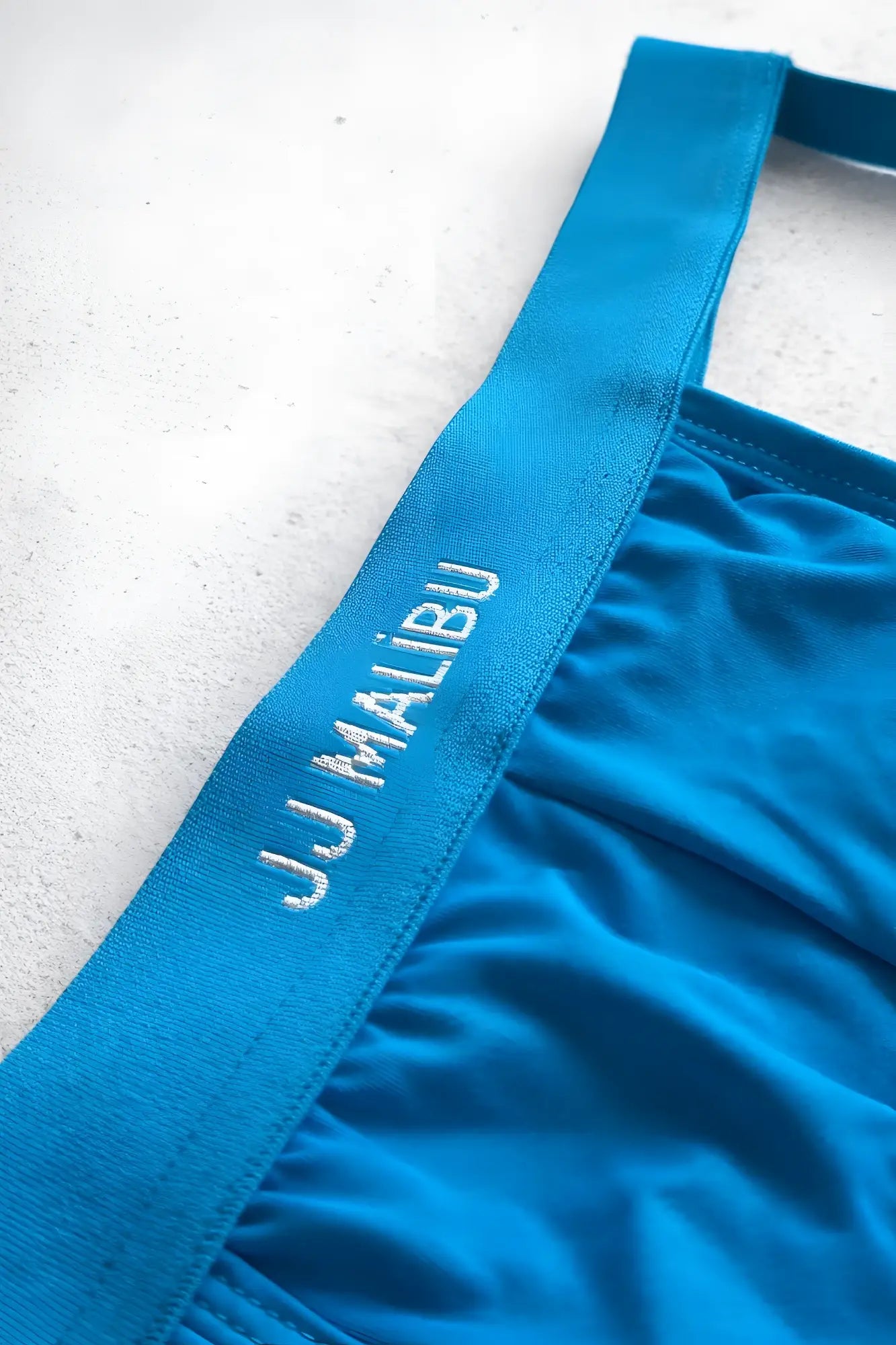 Bright blue jj malibu branded waistband with silver embroidery on the back of host-or-travel adjustable jock thong