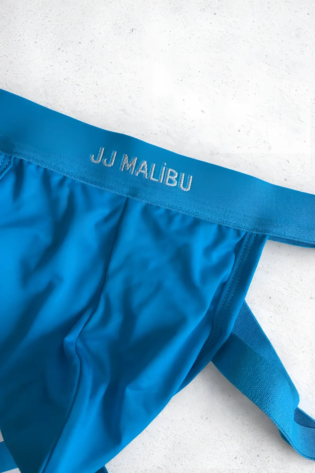 Bright blue jj malibu men’s adjustable jock thong with matching elastic waistband and side ties for travel or hosting