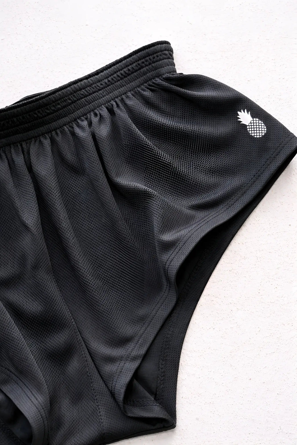 Stretch-it 2 inch quick-dry black mesh athletic shorts featuring a white pineapple logo on the side