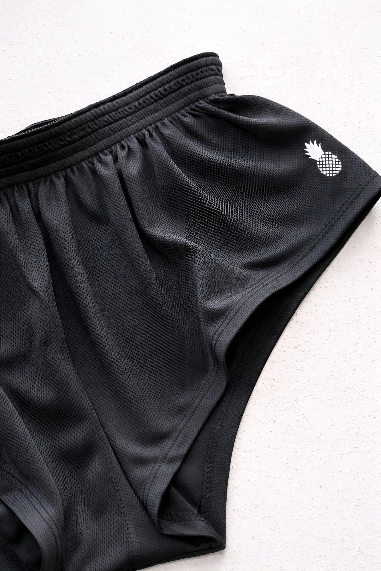 Stretch-it 2 inch quick-dry black mesh athletic shorts featuring a white pineapple logo on the side
