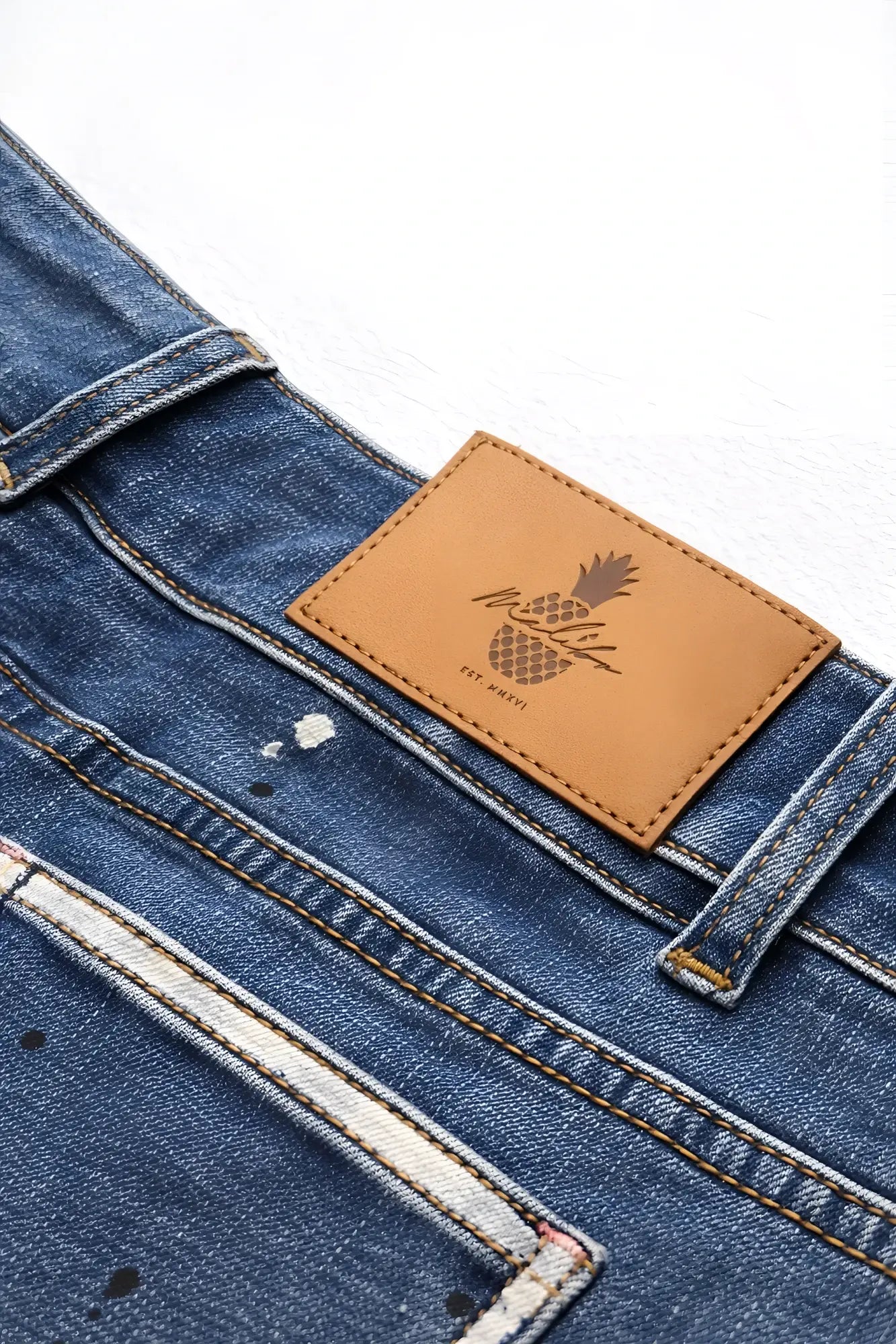Studio splash 1.5 inch dark blue denim short shorts with a tan leather patch embroidered pineapple logo on back