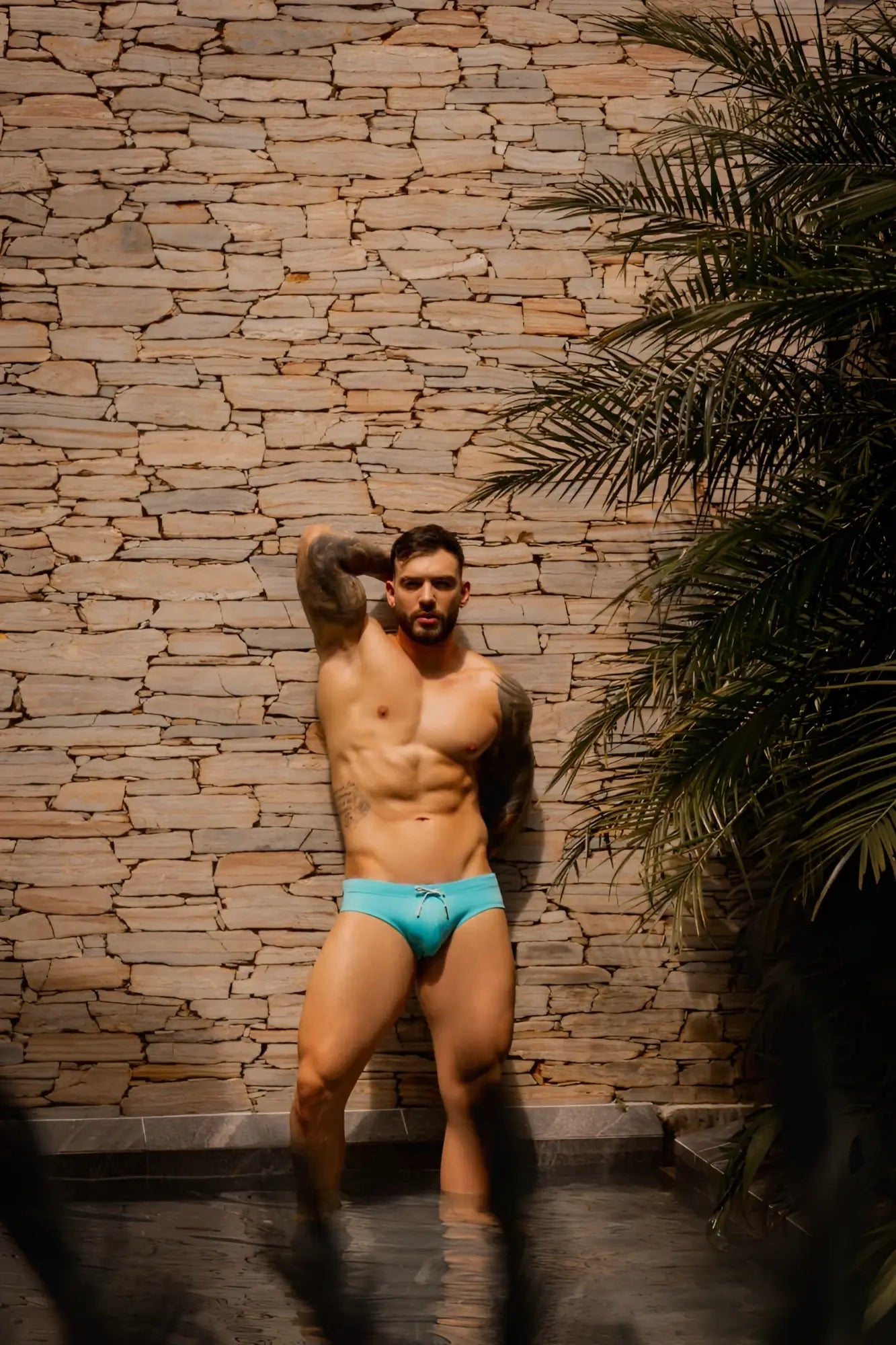 A man wearing bright turquoise jor 2387 travel swim briefs with a simple drawstring waistband for swimming and travel