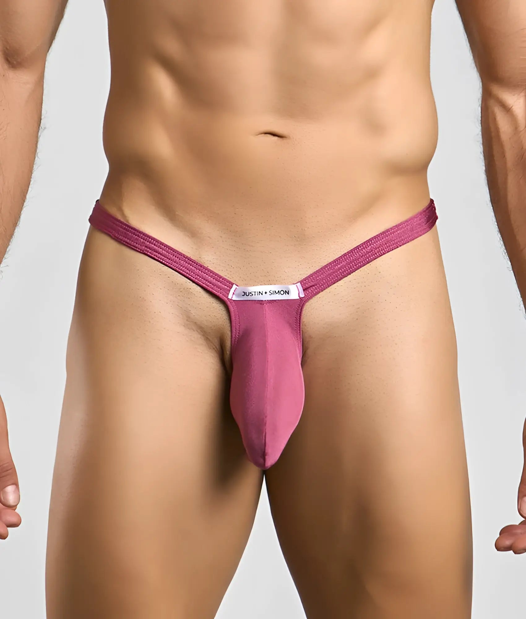 A magenta form-fitting thong with a central pouch and white justin + simon label for bulge enhancement