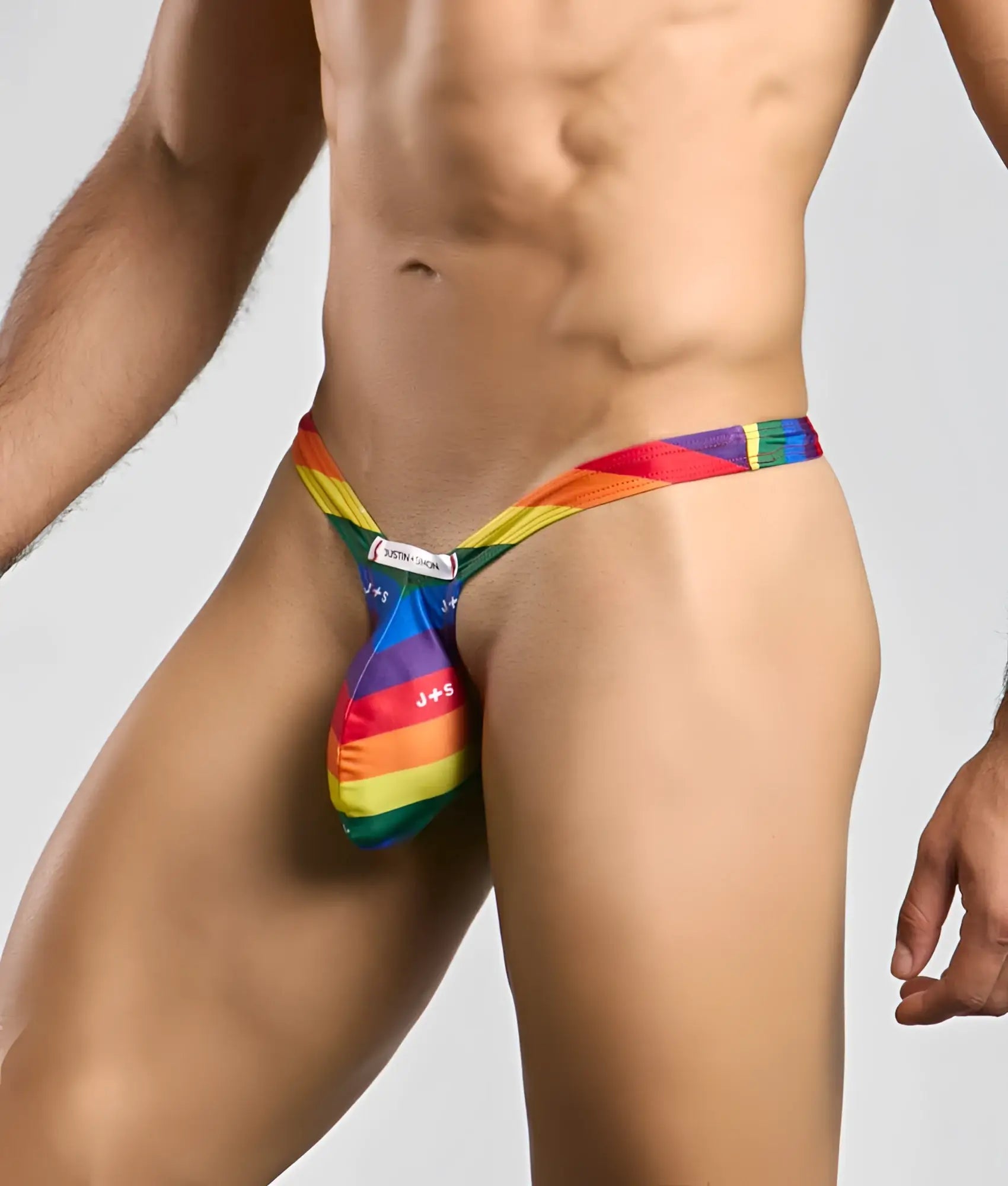 Justin + Simon bulge thong rainbow-striped men’s jockstrap with vibrant multi-colored fabric design front view