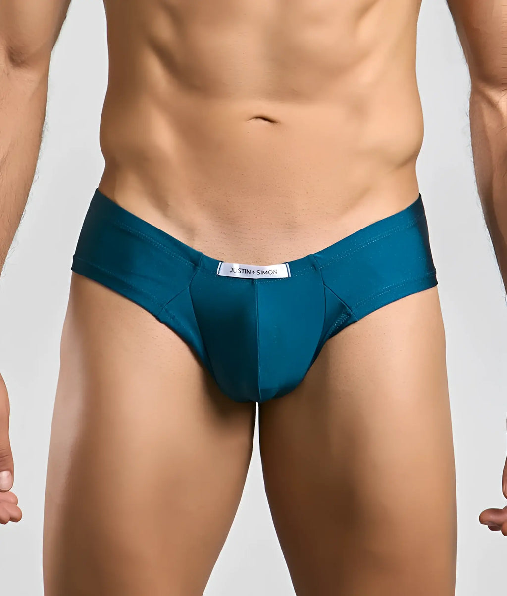 Teal-colored form-fitting briefs in sleek smooth fabric with a white Justin + Simon brand tag at the waistband