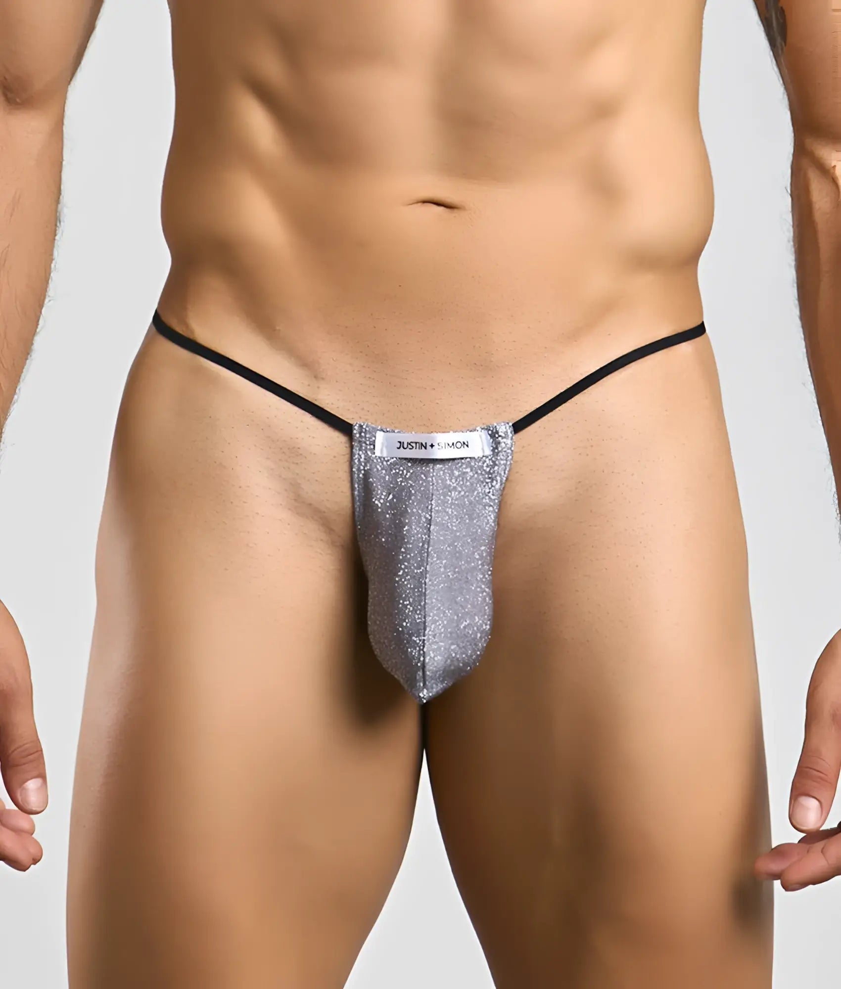 Silver glittery thong with black elastic waistband and white justin simon label from Justin + Simon classic g-string bulge