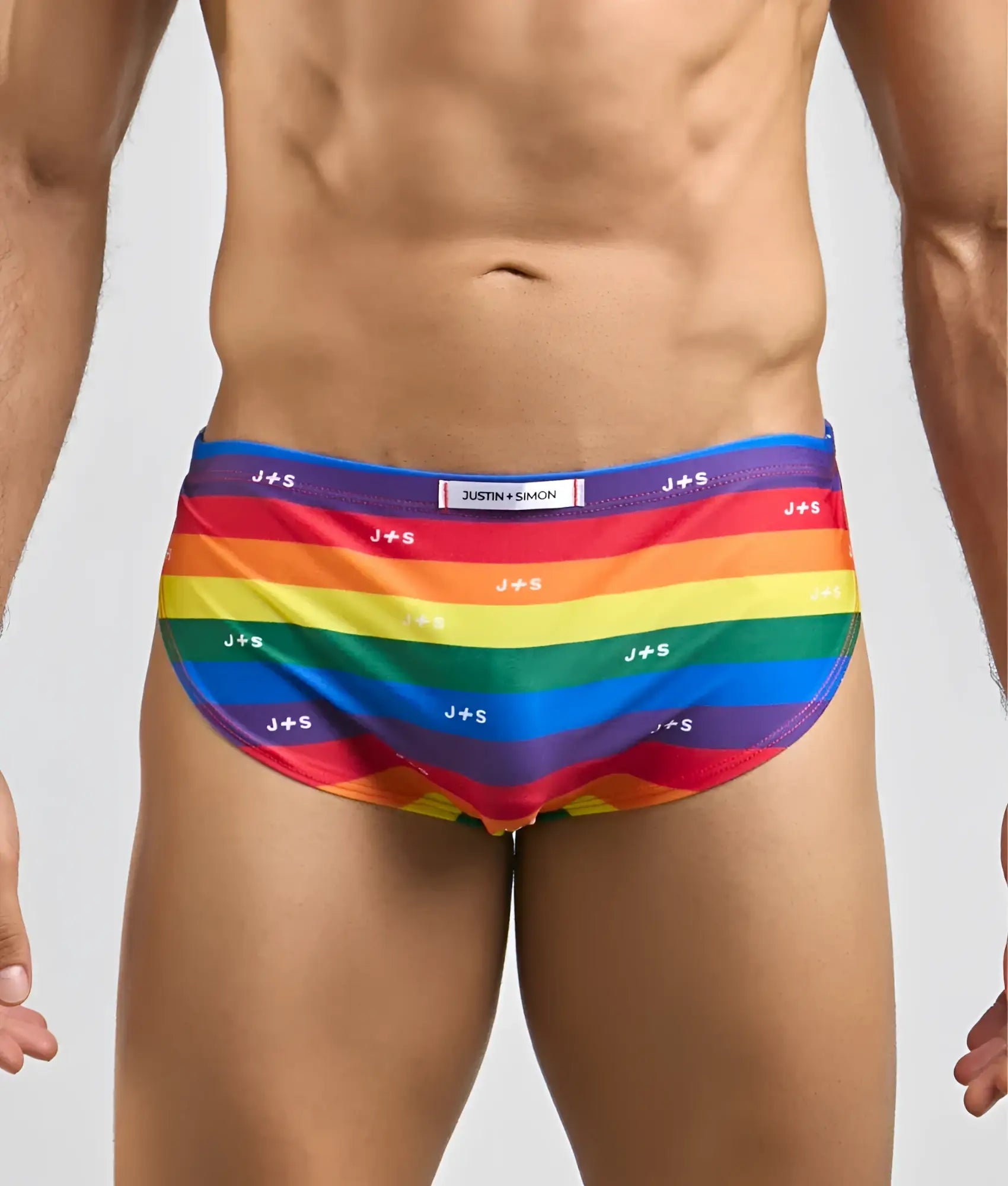Justin + Simon running short rainbow-striped men’s swim trunks with vibrant colors and repeating j+s branding