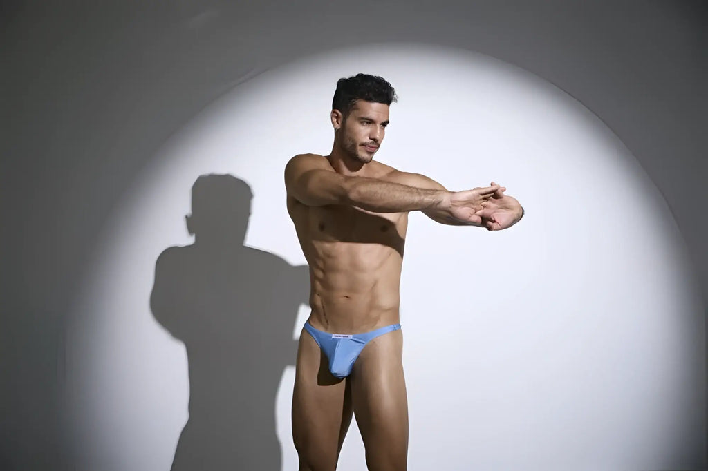 A man wearing justin simon xsj03 classic baby blue briefs with a small white logo on the front in a form-fitting style