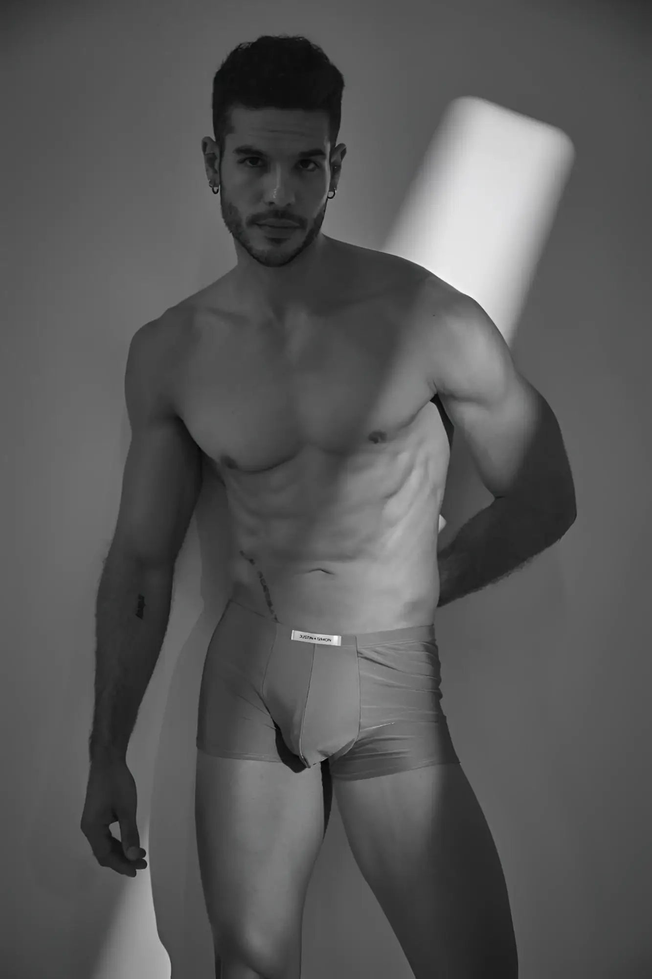 A man wearing light-colored form-fitting calvin klein classic boxer underwear in metal green color with visible waistband label