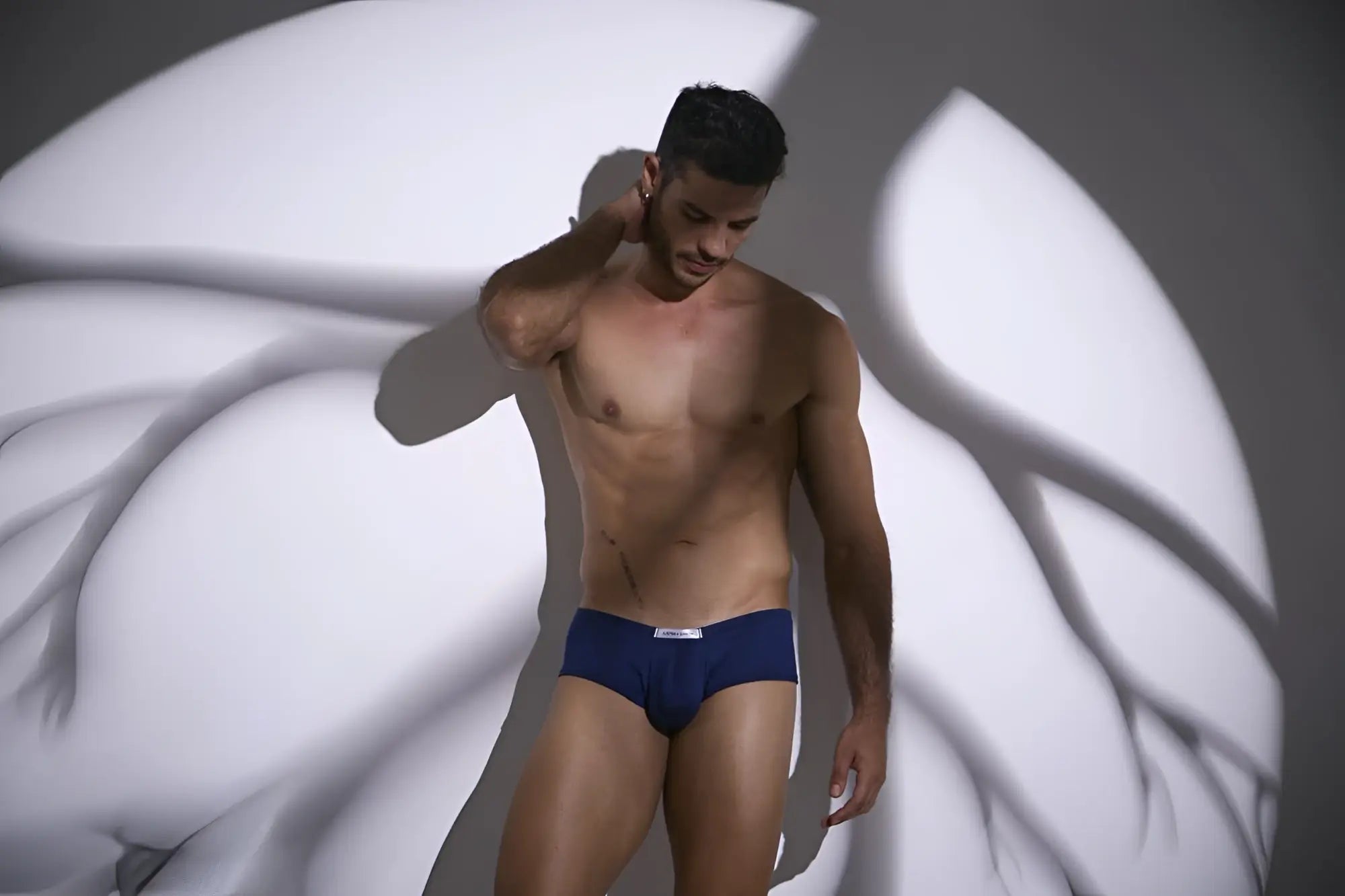 Navy blue justin simon cheeky bulge boxer briefs with a small white logo on the waistband in color peach navy