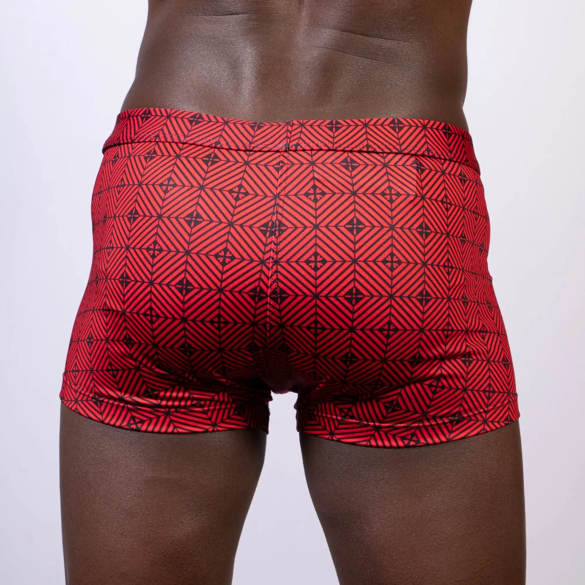 Red swim trunks with a black geometric pattern featuring KALEIDOSCOPE SQ CUT TRUNK design for swimming use