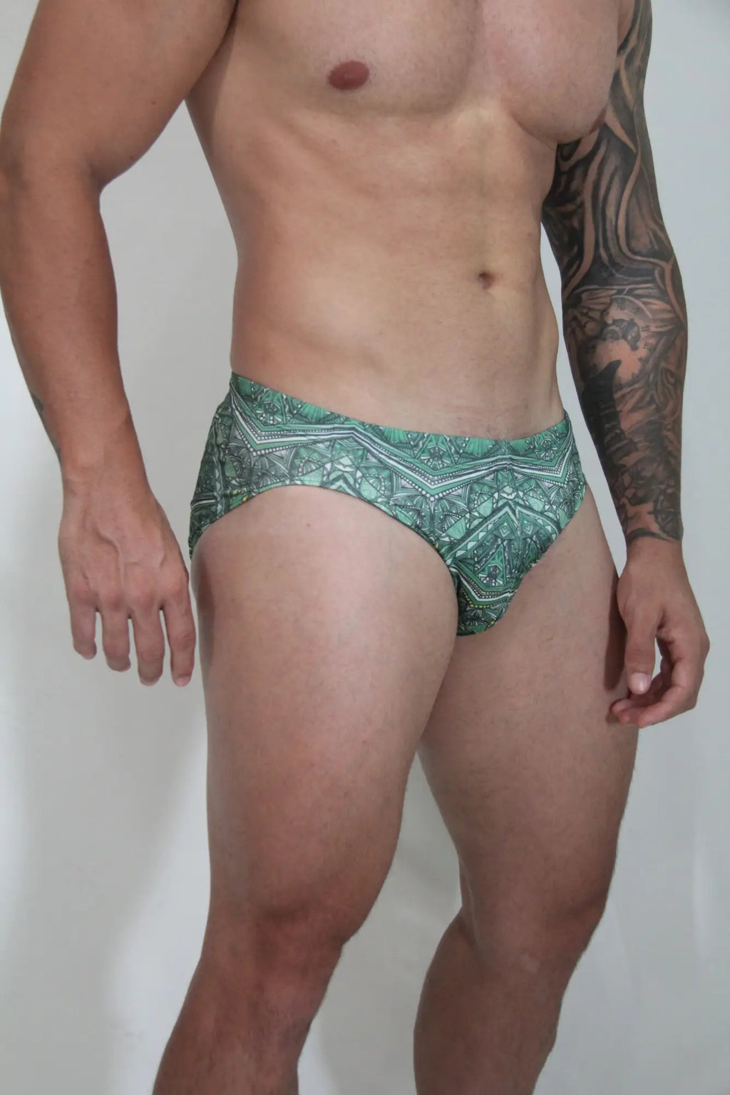 Green patterned kaleidoscope swim brief with intricate geometric designs ideal for beachwear and swimming use