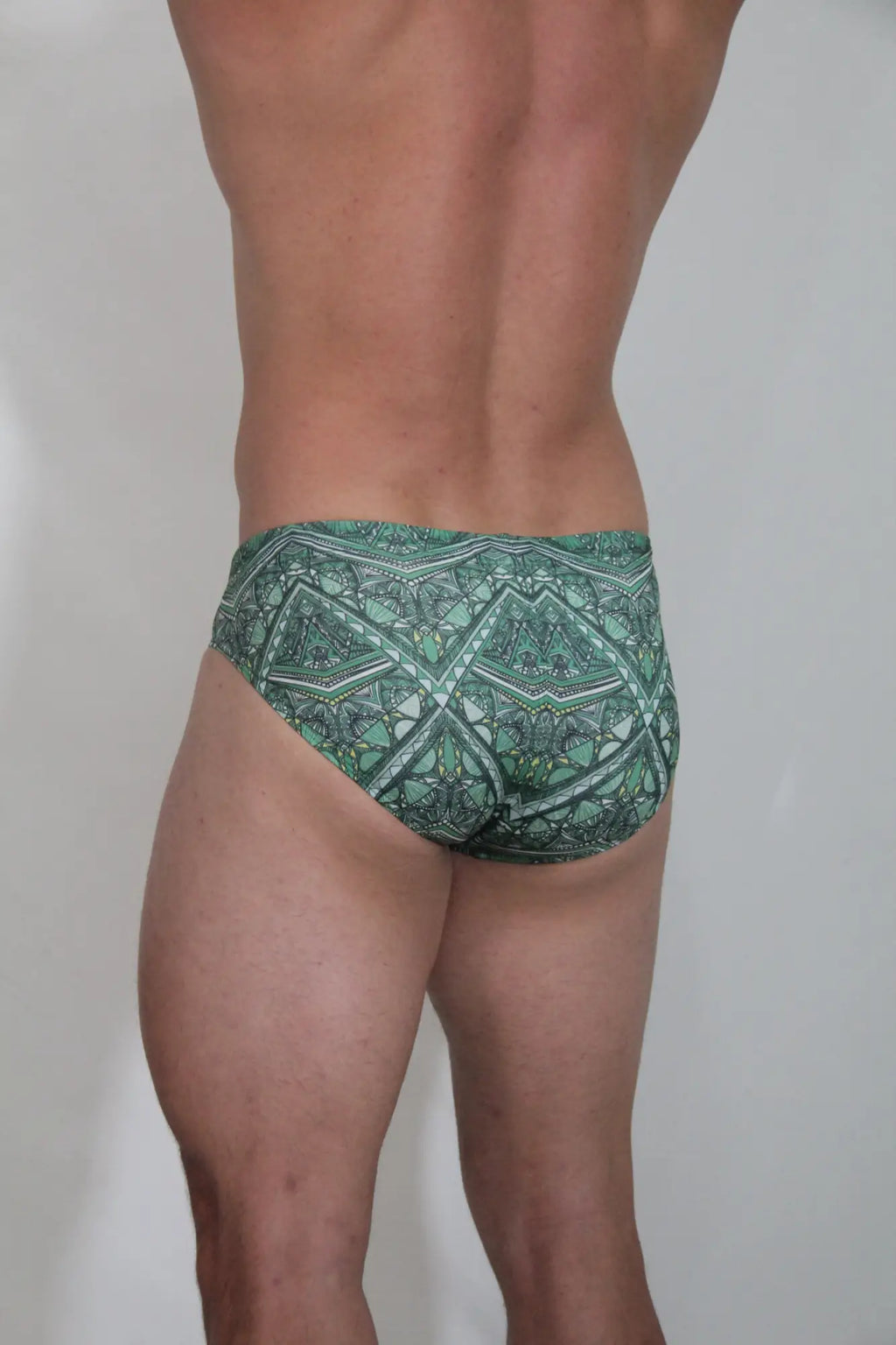 Green patterned kaleidoscope swim brief with intricate geometric and tribal-inspired designs for beachwear