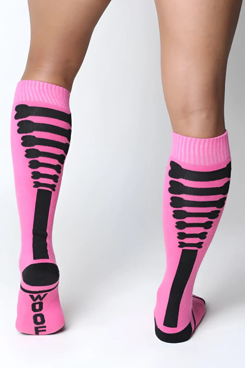 Pink kennel club bones knee high socks with black skeletal bone patterns and wool printed on the heel showing back side