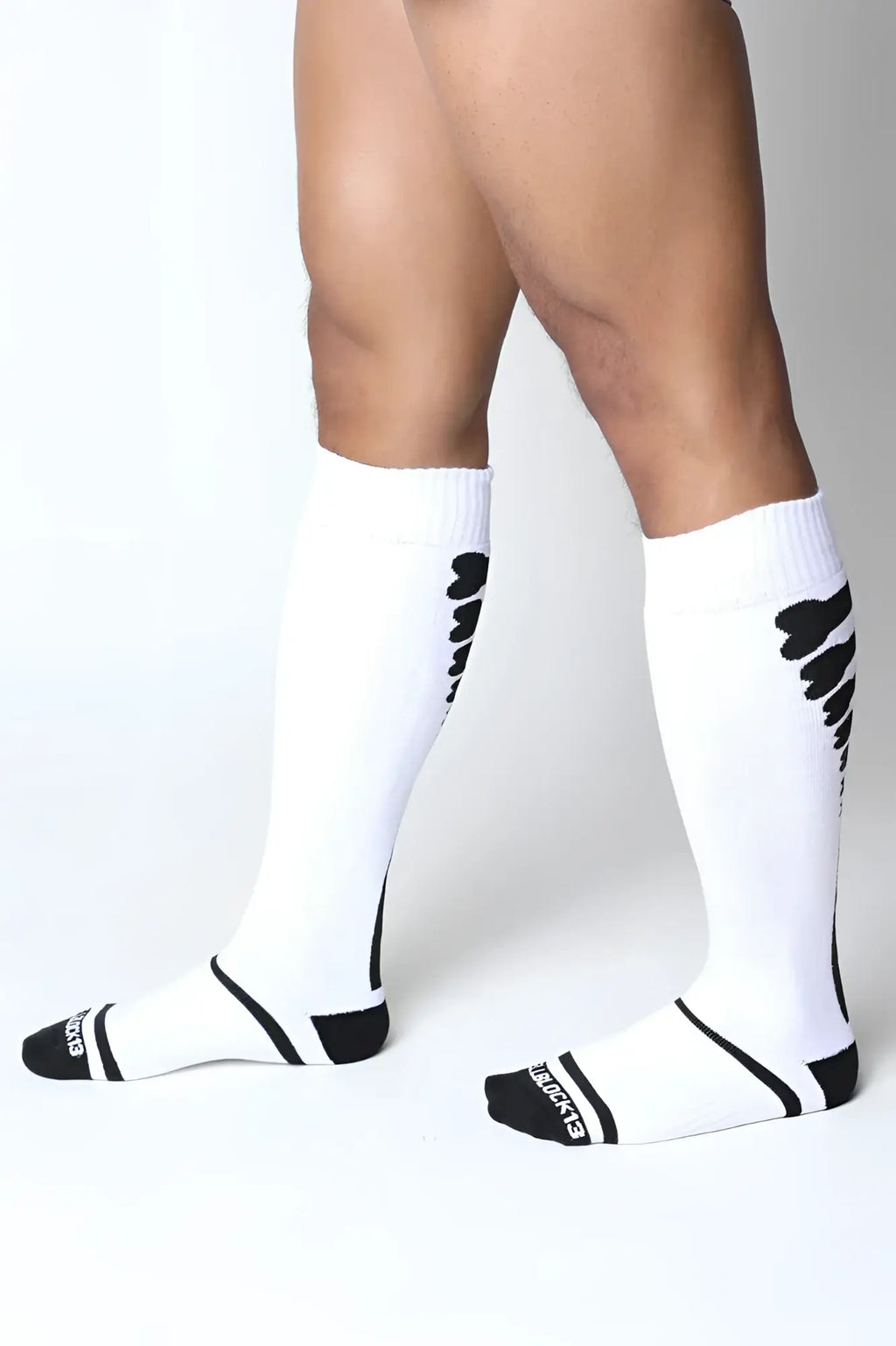 White kennel club bones knee high athletic socks with black wing patterns and heel branding shown from the back side